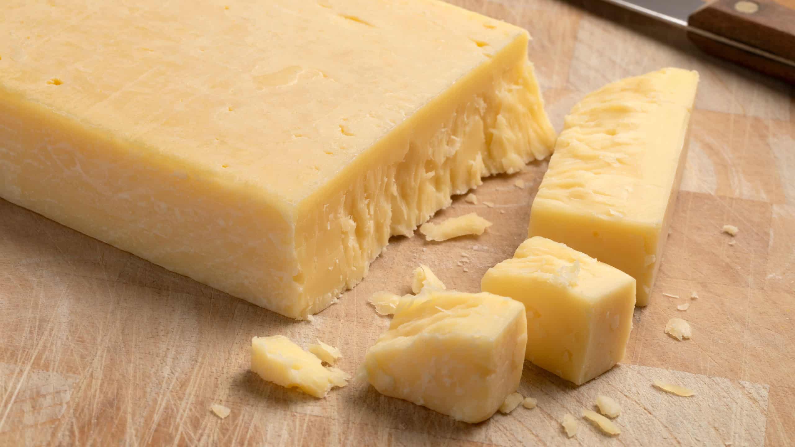 Extra mature english traditional cheddar cheese and pieces on a cutting board