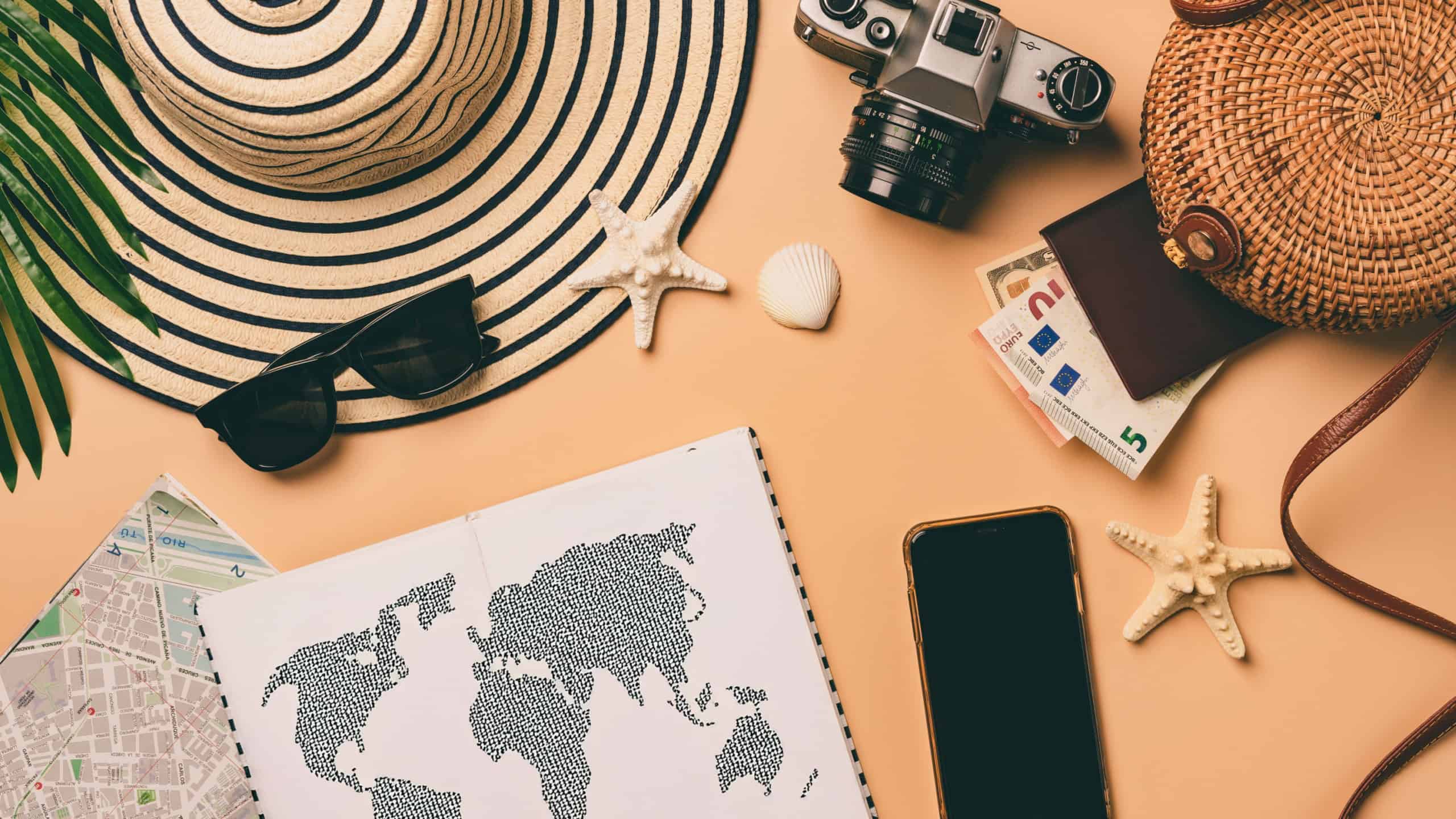Top view travel concept with retro camera films, map and passport on light orange background with copy space. Flat lay tourist essentials