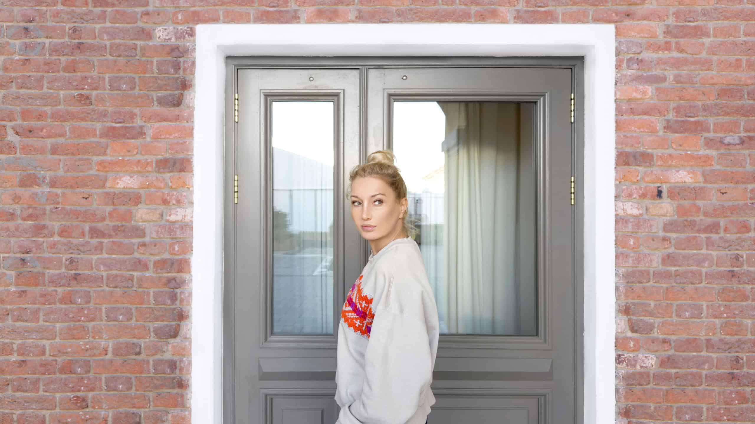 Young woman opening the door of the house