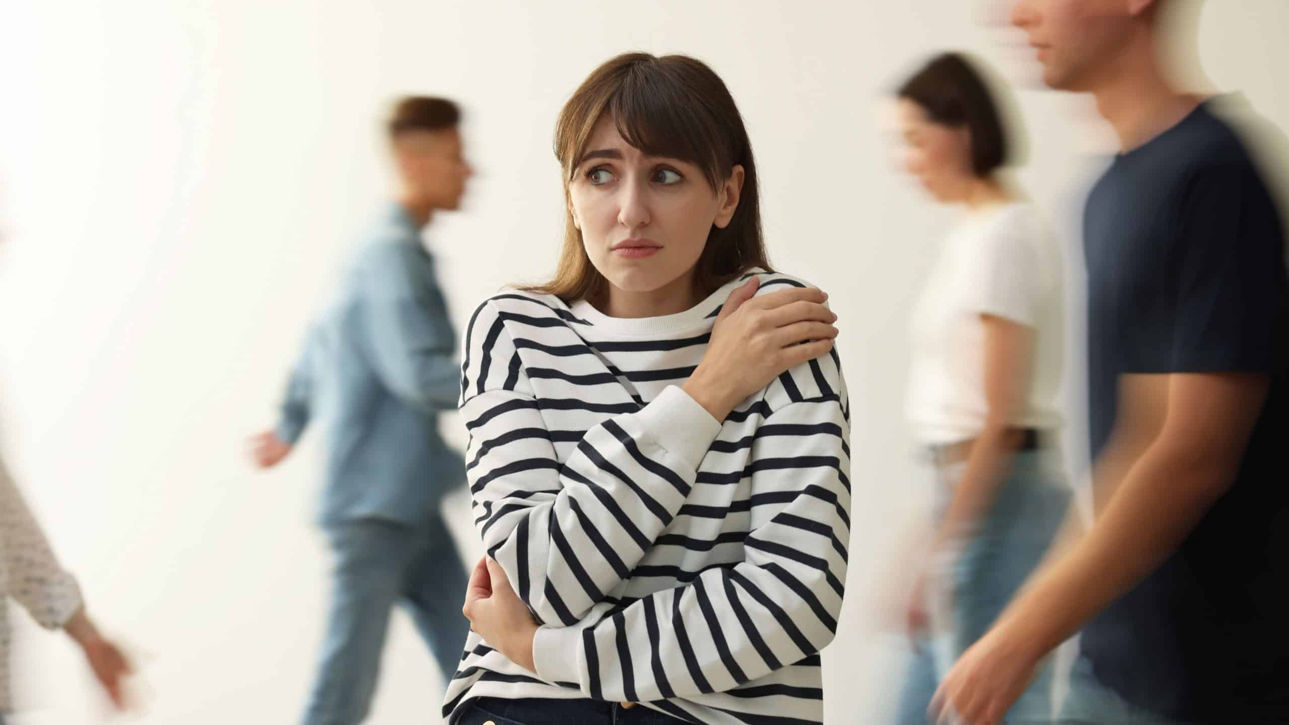 Young woman feeling uncomfortable among people indoors
