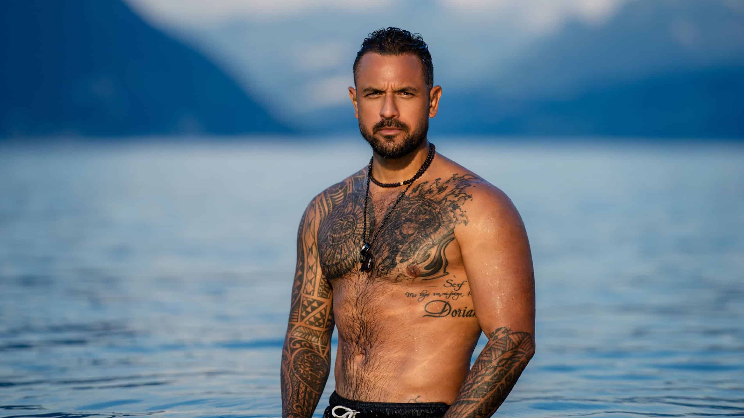 Shirtless muscular man swimming in a lake. Handsome athlete enjoying water in nature. Fit male model posing by the beach. Strong man splashing in a mountain lake. Sexy guy swimming in the sea.