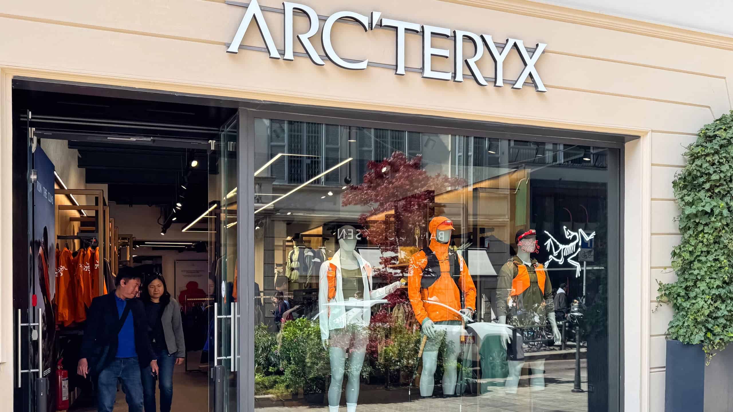 Milan, Italy - April, 07, 2025: Storefront of Arc'teryx retail shop with mannequins in outdoor sportswear and open glass entrance. Urban commercial architecture and shopping concept. Frontal view.