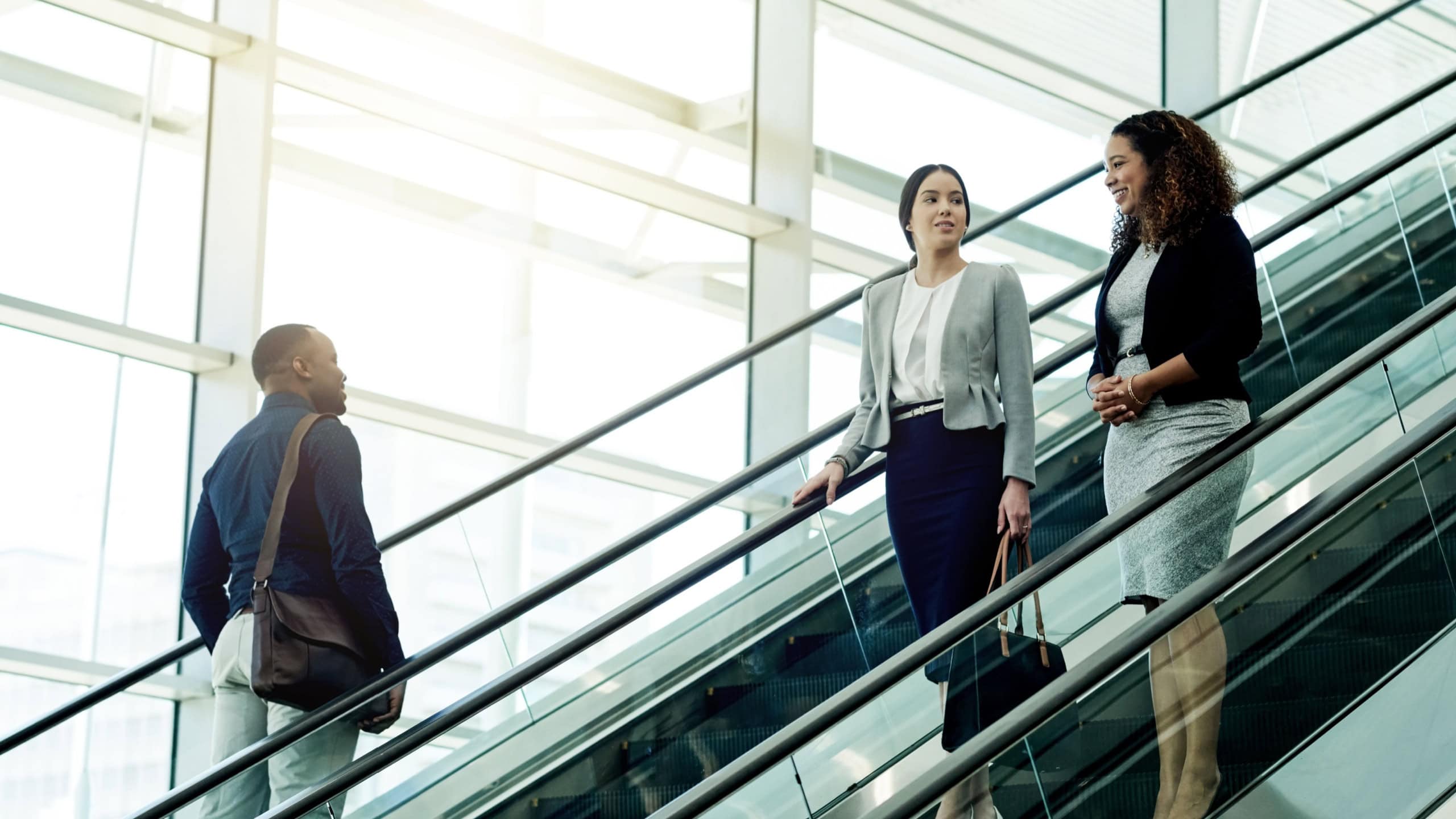 Employees, escalator and morning in office building for business, new day or coworkers on lift. People, corporate team or stairs in company with meeting schedule, discussion or planning productivity