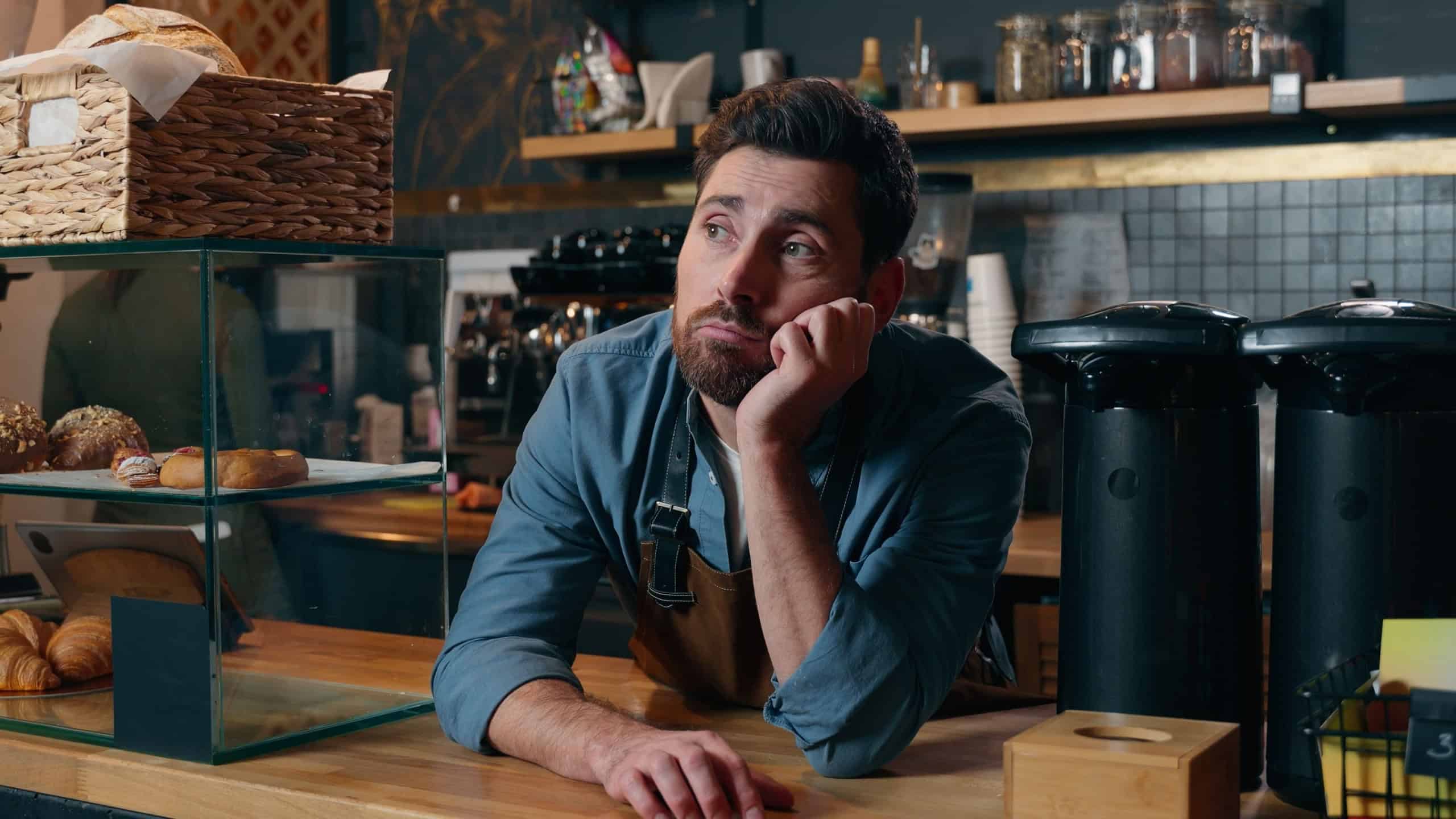 Frustrated Caucasian bartender man staff guy waiting clients in coffee shop bored employer working small business owner feeling stress cafeteria upset male barista no customers problem cafe difficulty