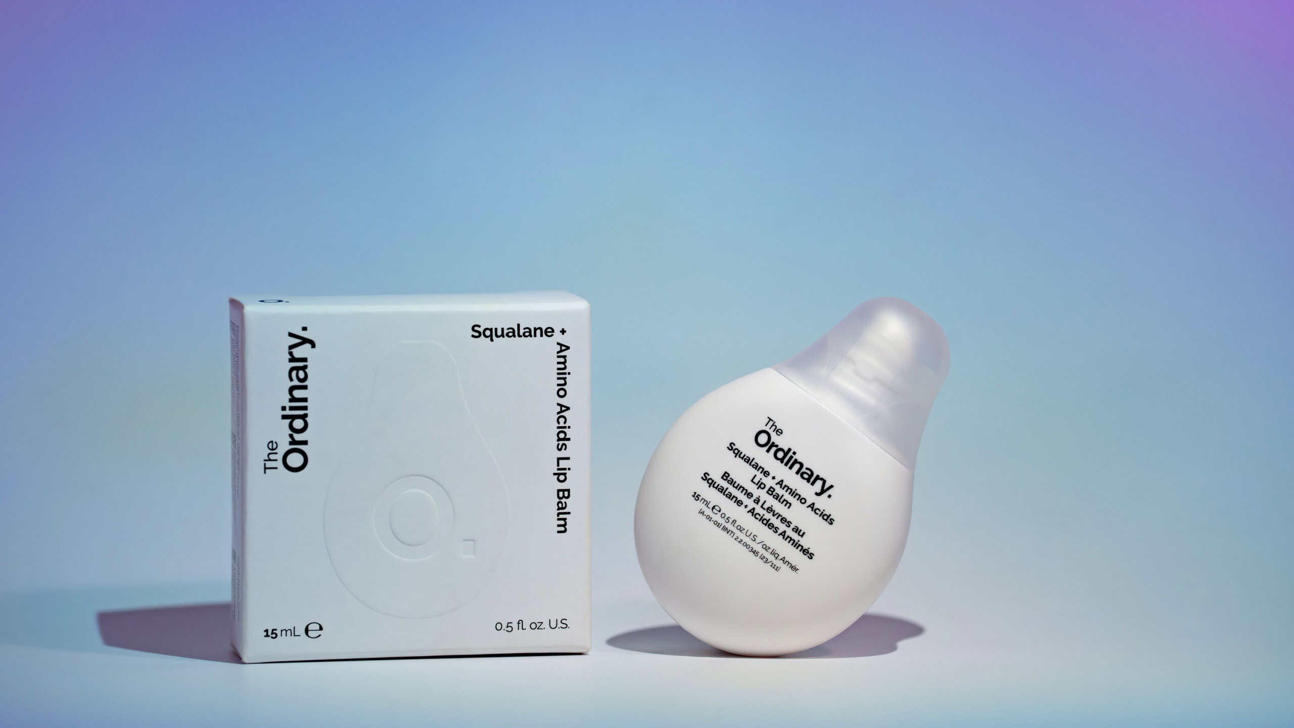 The Ordinary Moisturizing Lip Balm. Minimalist product photo of tube packaging and box in pastel blue holographic light