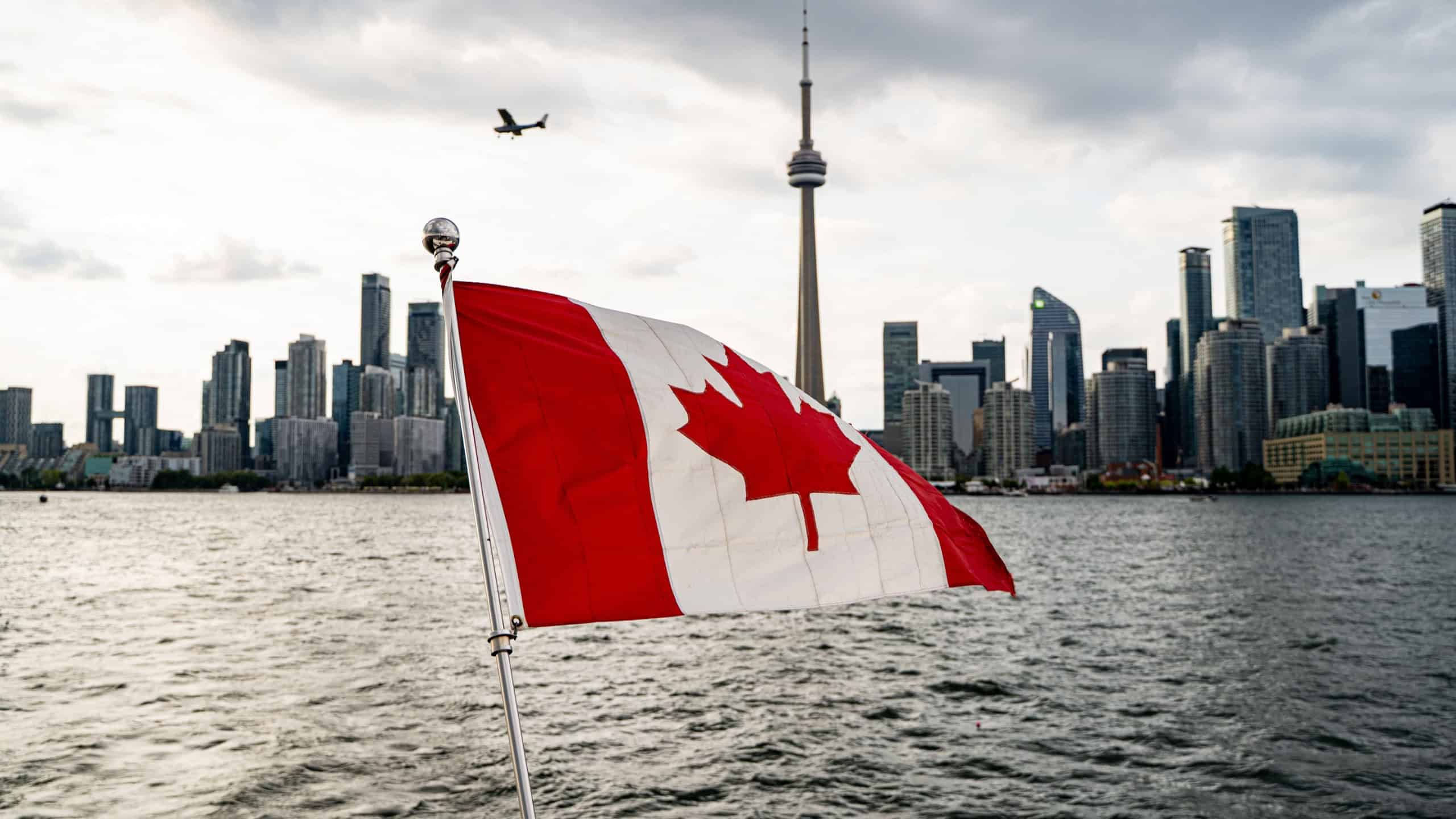 View of Canadian flag with Toronto skyline in background. Toronto, Canada - August 23, 2025.