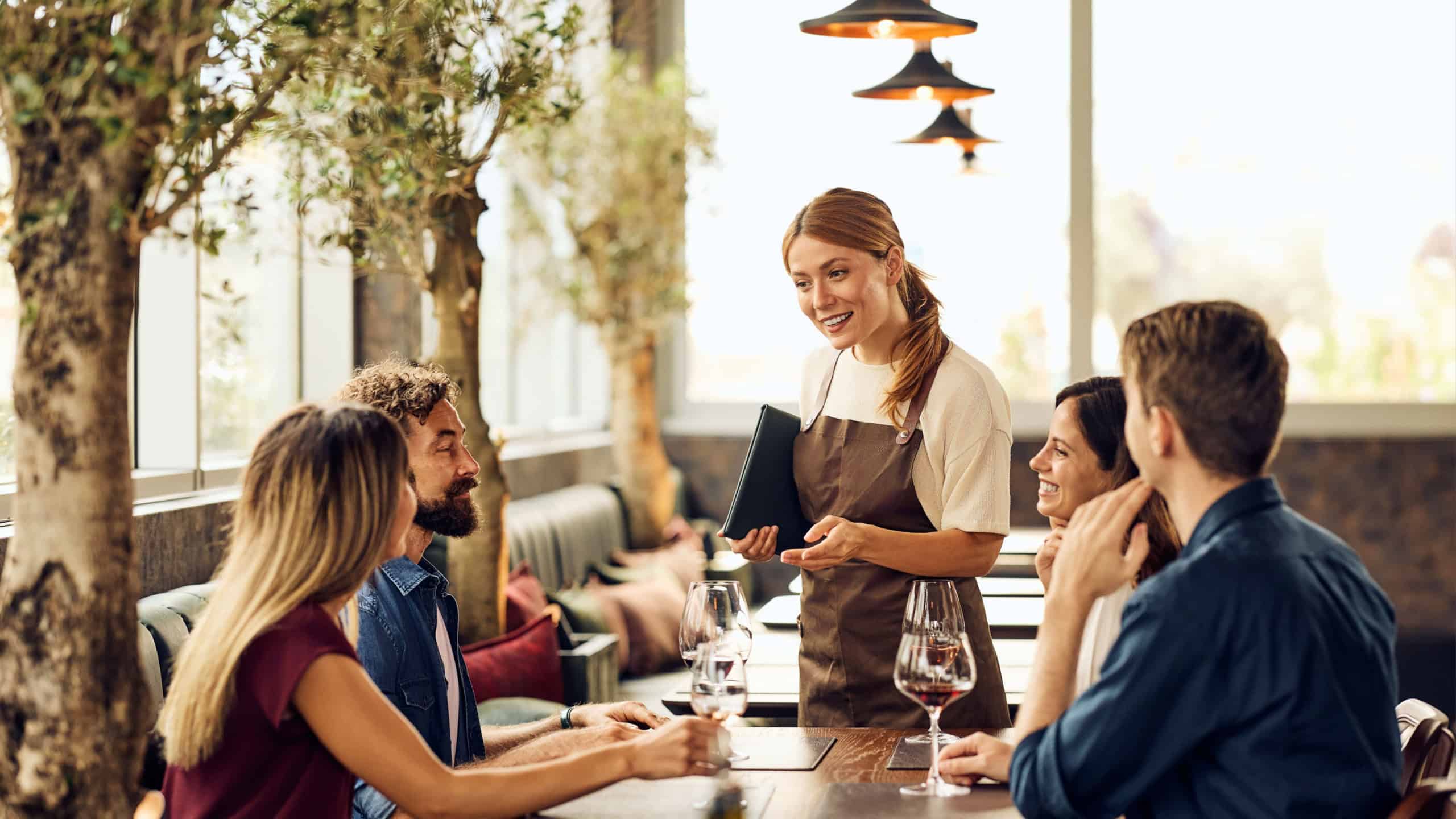 Friends enjoy a fine dining restaurant experience with attentive service and conversation.