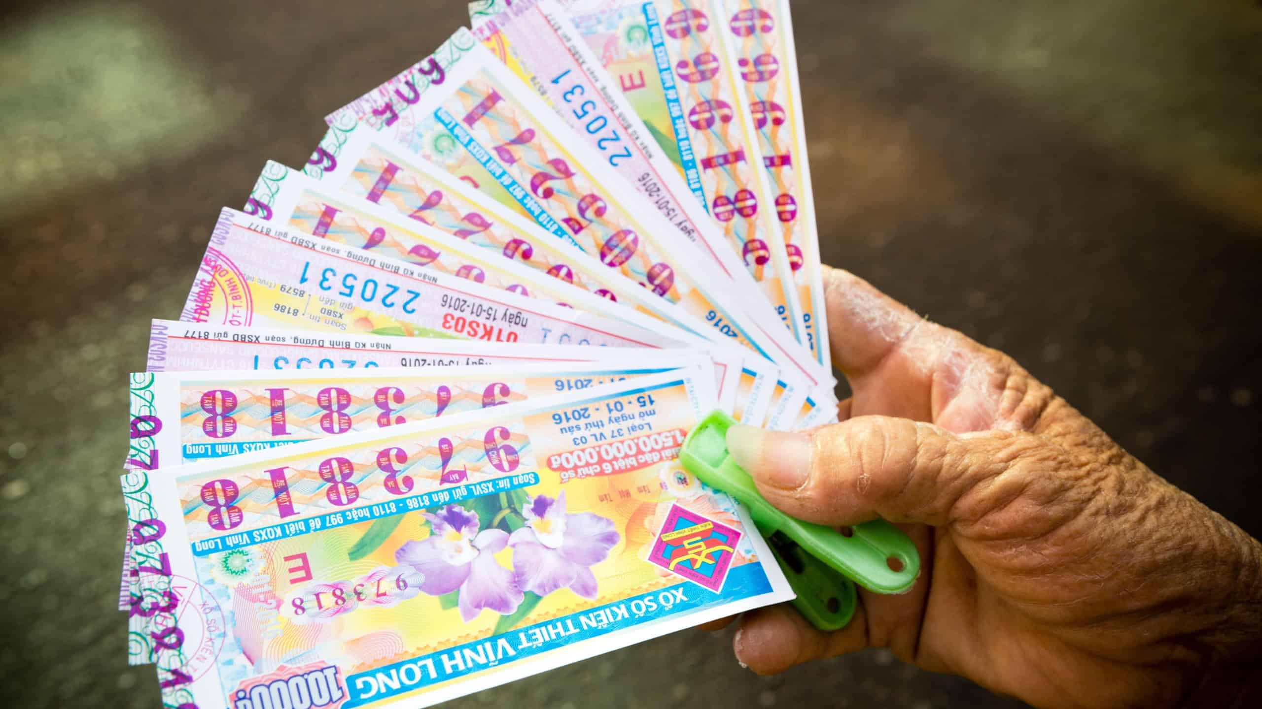  A lottery ticket seller street vendor holding a fanned out display of Vietnamese lottery tickets in Ho Chi Minh City, Vietnam.