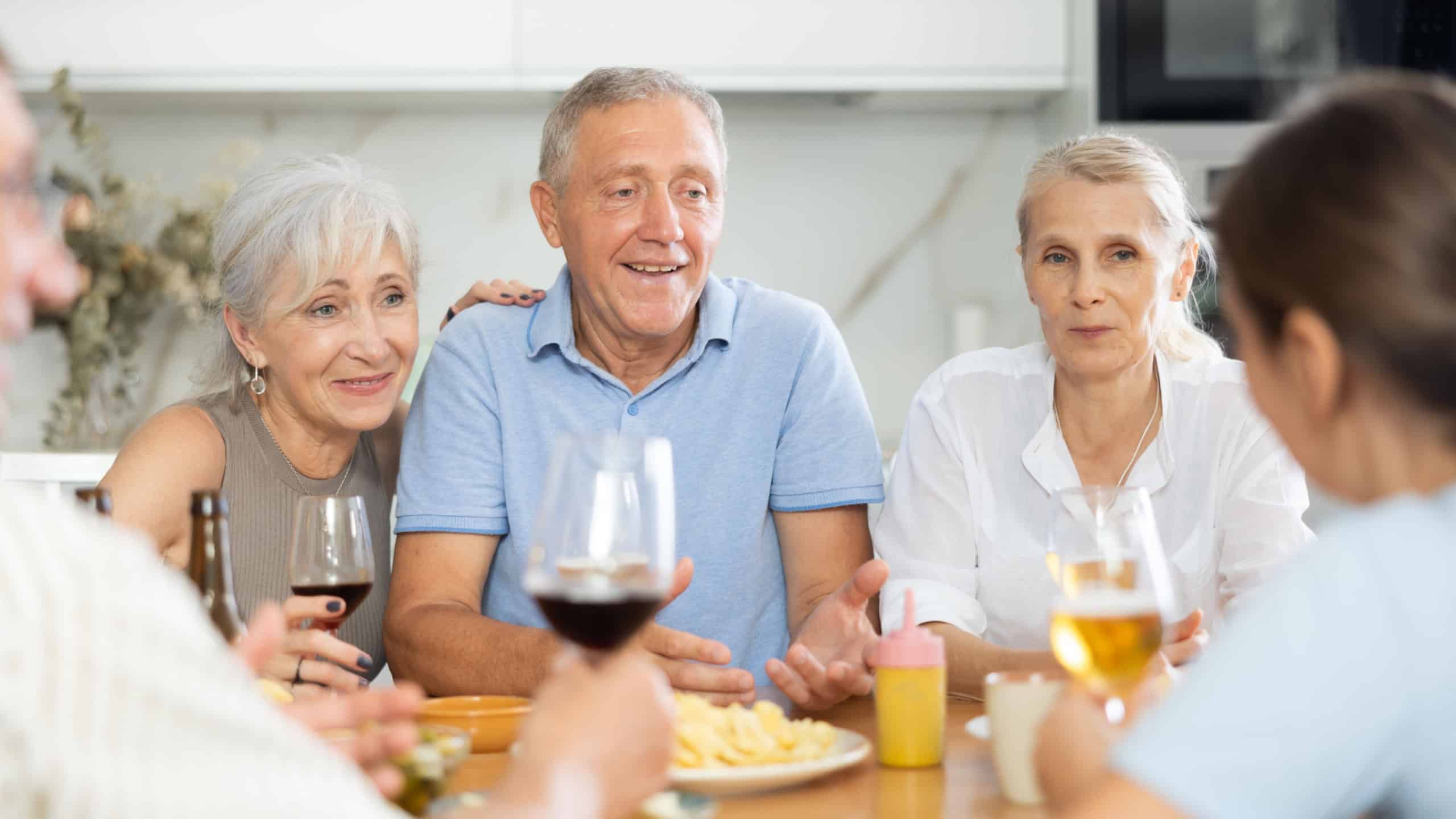 Happy seniors chatting at dinner table. Concept of happy life together in a nursing home