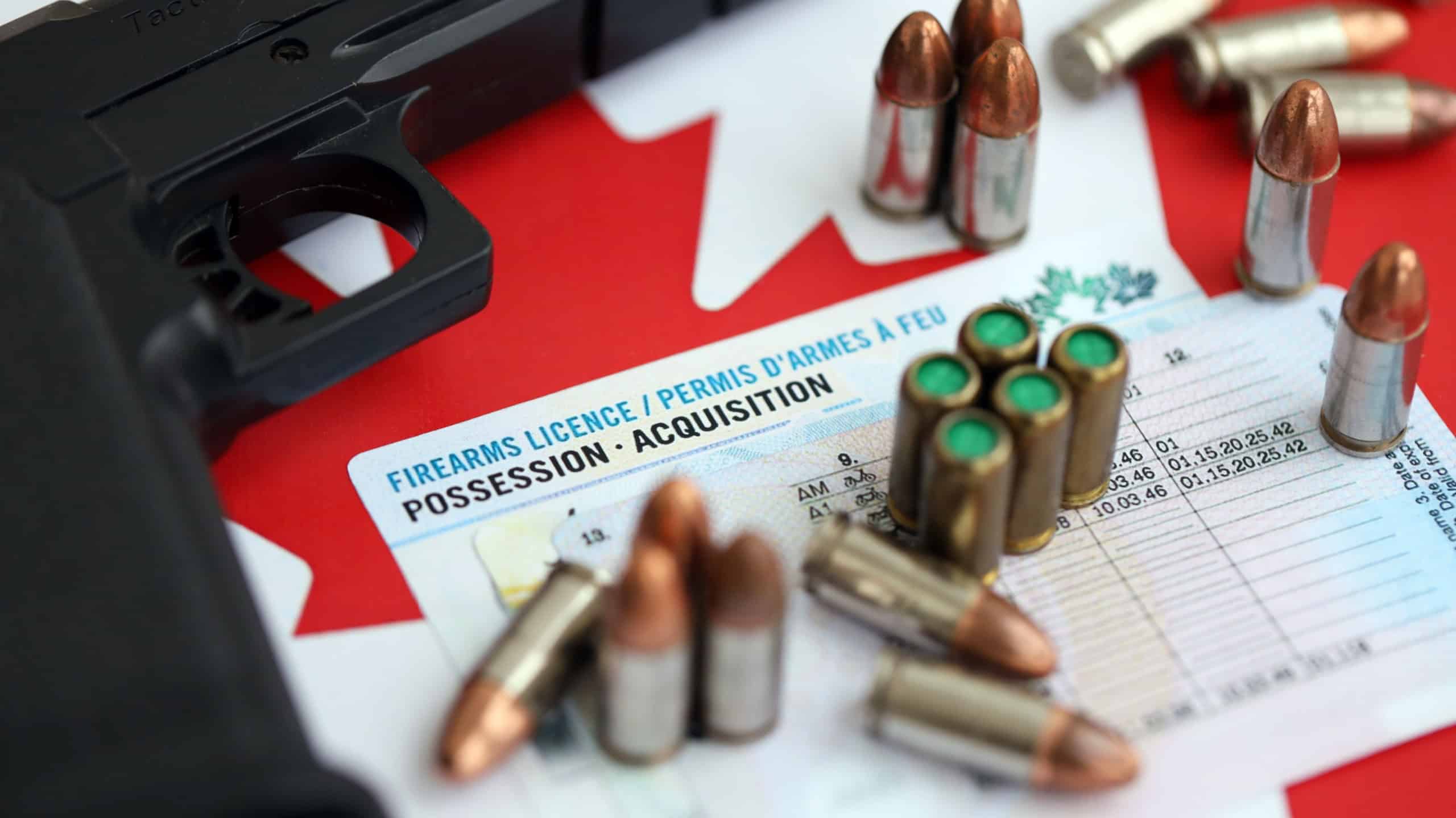 Canadian firearms license and handgun with bullets on Canadian flag close up. Gun permit concept. Concealed pistol permit