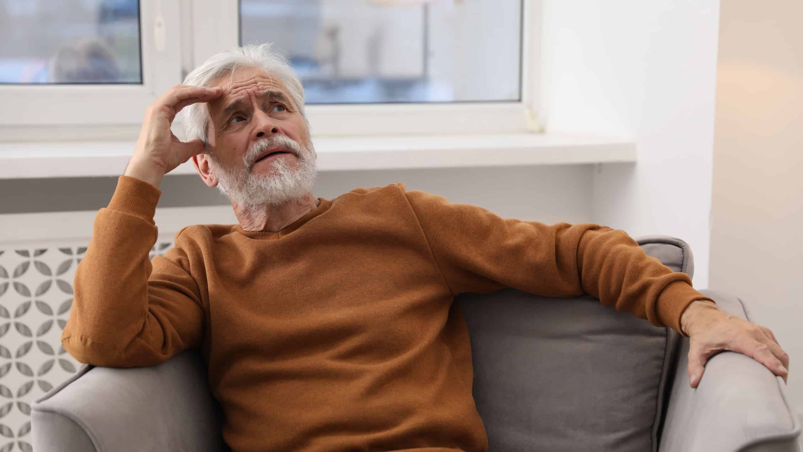 Amnesia. Senior man trying to remember something at home