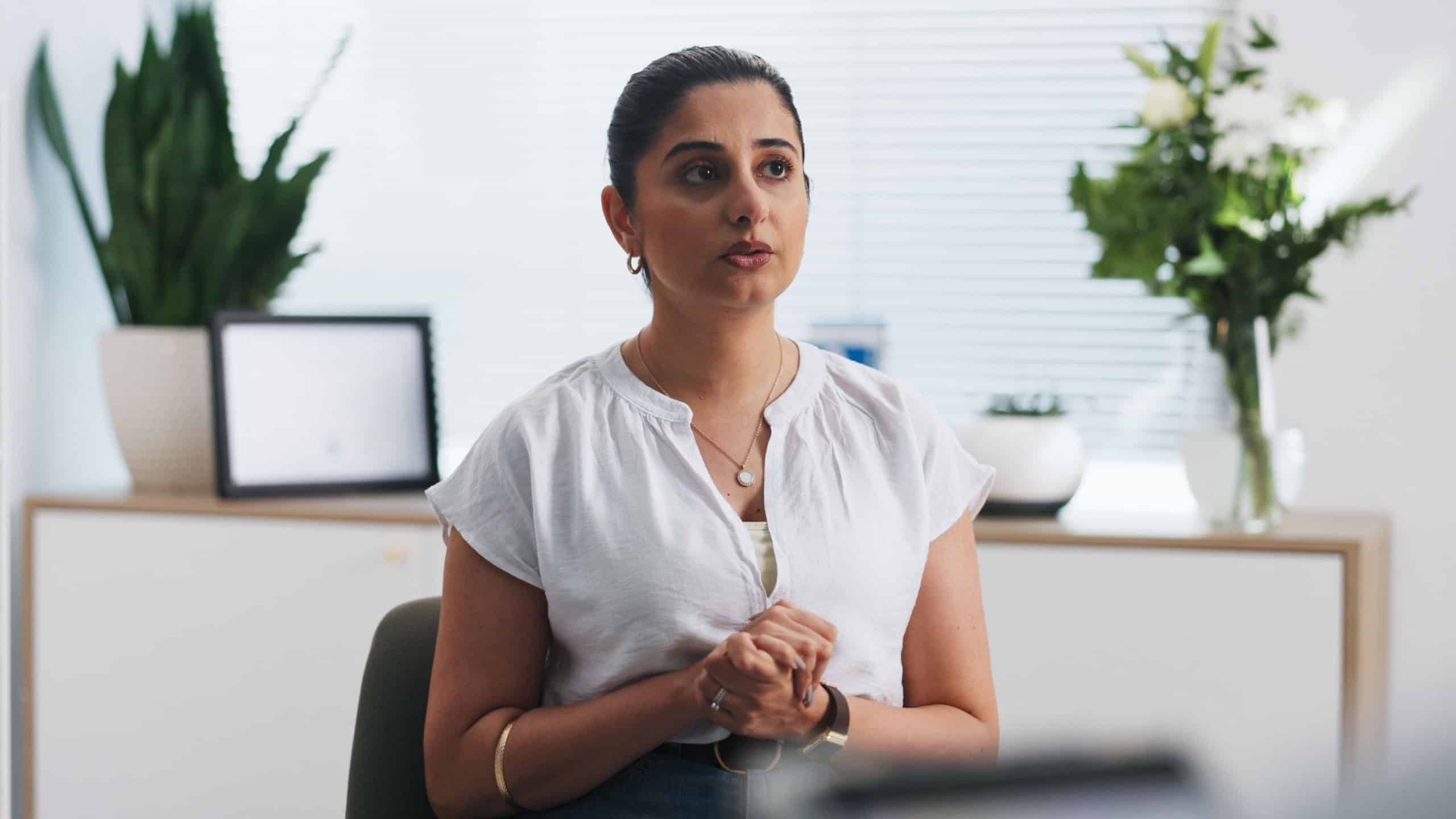 Woman, talk and nervous with therapy at clinic, pov and explain symptoms for anxiety in consultation. Person, psychology and discussion for stress management, advice and mental health at hospital