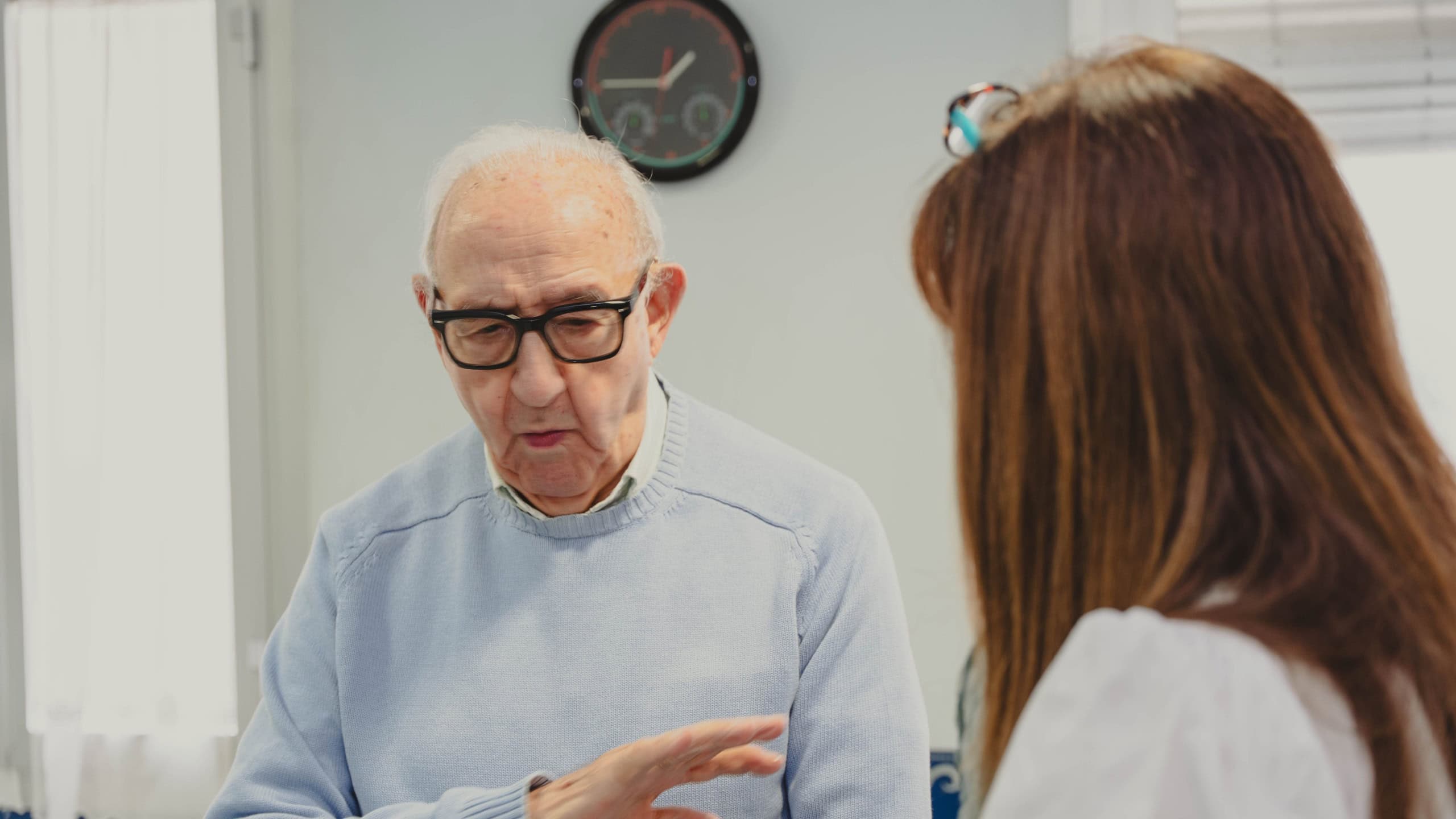 Elderly man talking with his adult daughter, showing family support and care indoors