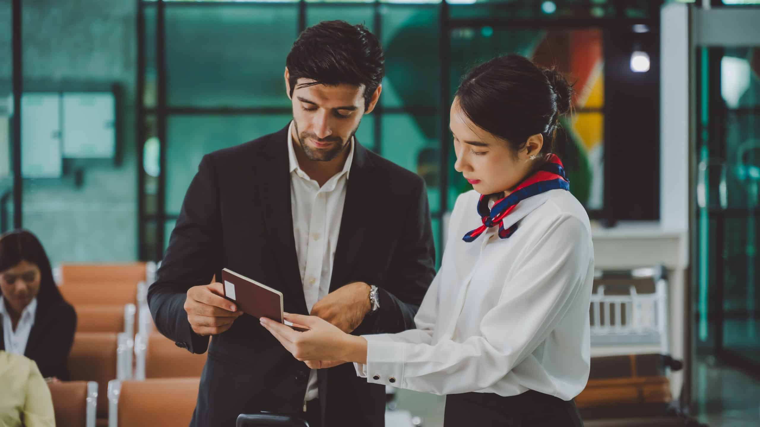Airline ground staff assisting business traveler with passport verification at airport lounge