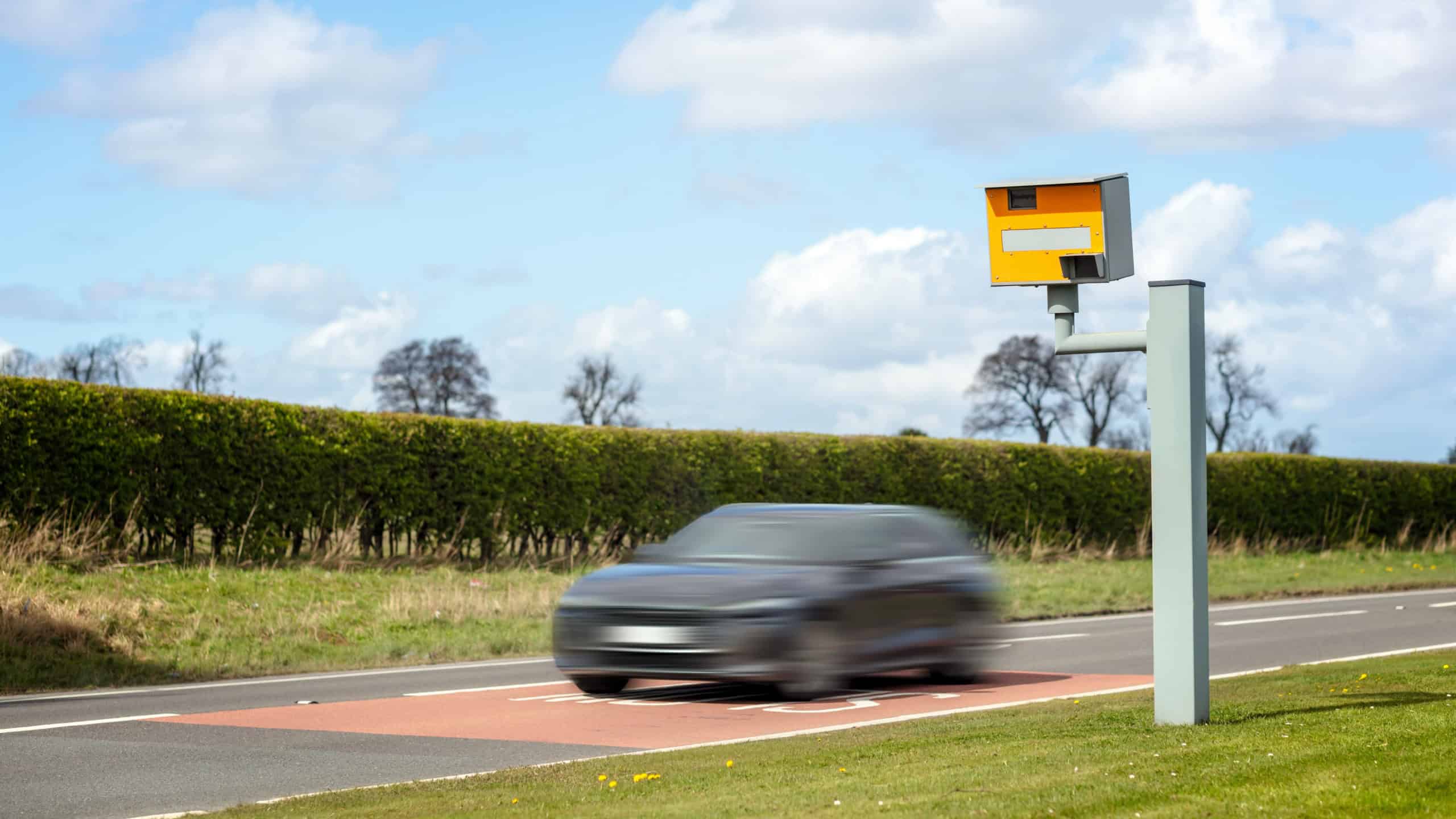 Radar speed camera and fast speeding car on the road in the UK