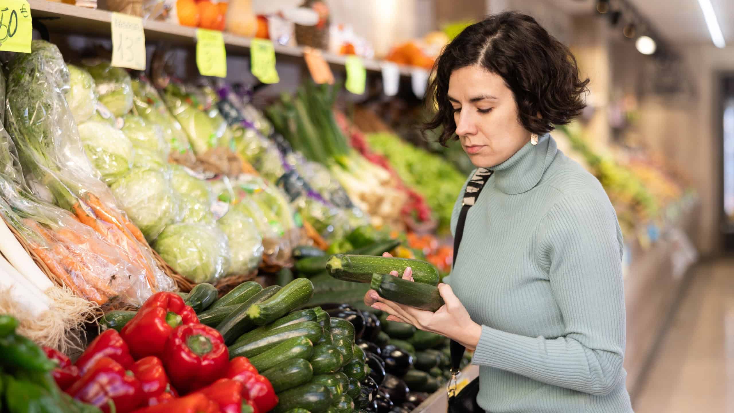 Woman carefully selects red bell peppers in a grocery supermarket