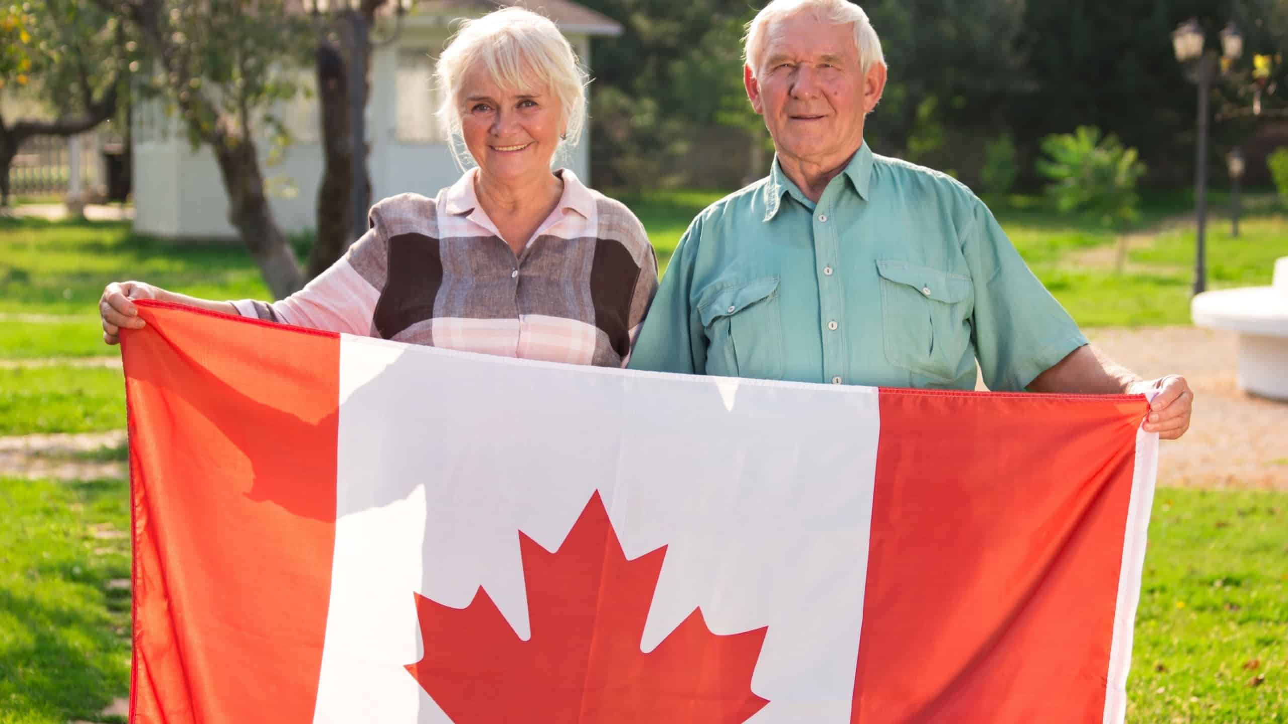 Senior couple holding Canadian flag. Man and woman outdoors. Life in Canada.