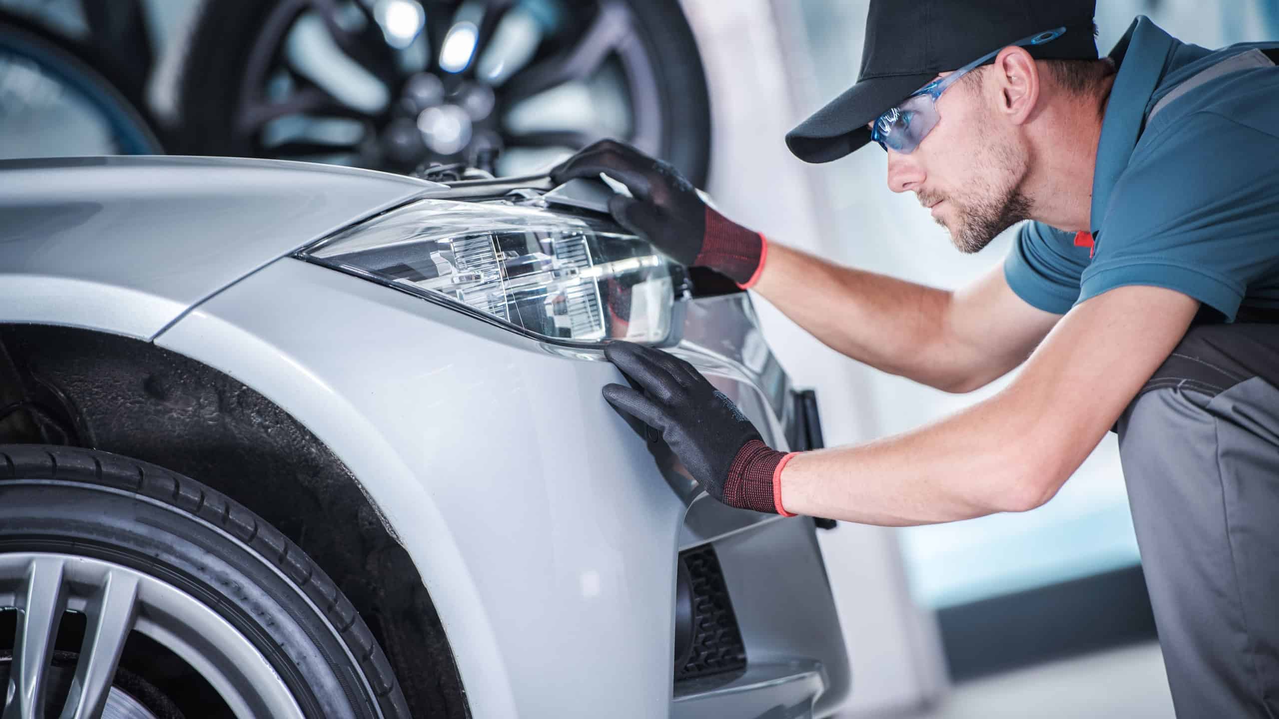 Aim and Adjust Car Headlights. Caucasian Worker in Front of the LED Vehicle Front Lamp Looking For Issues. Safety on the Road.