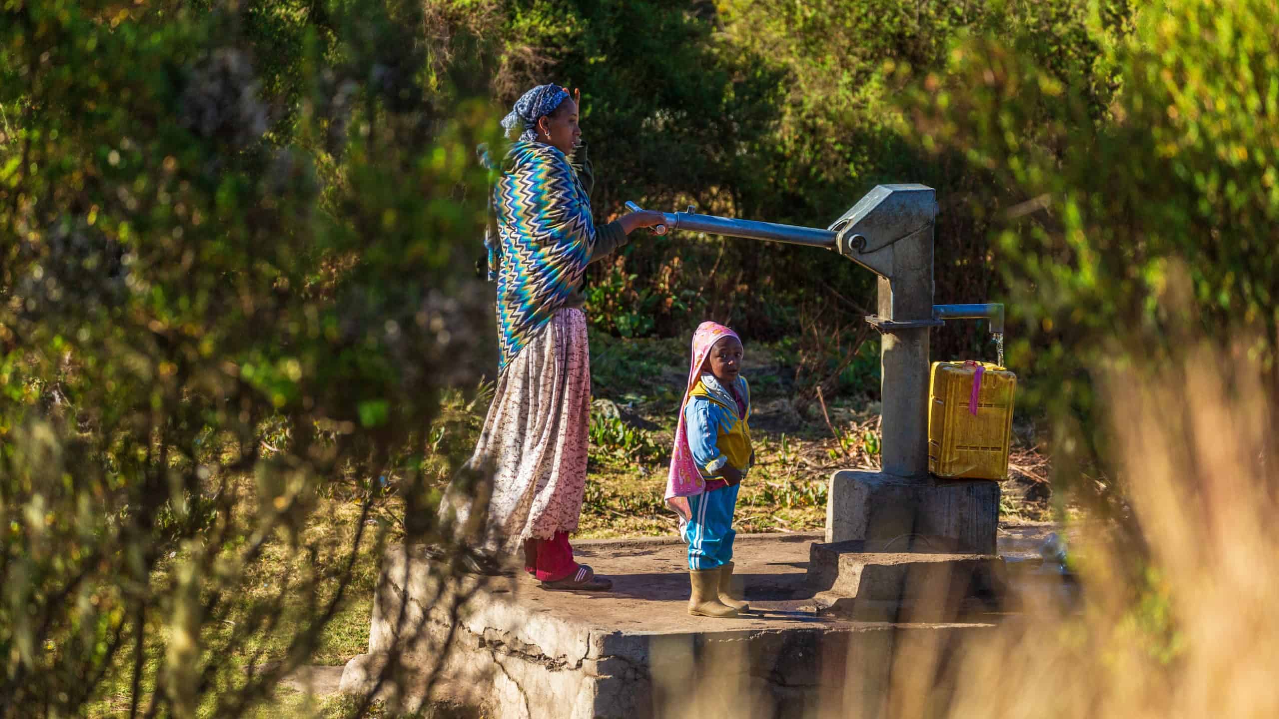 OROMIA, ETHIOPIA-JAN 21, 2019: Unidentified mother with child pumping water from a source.
