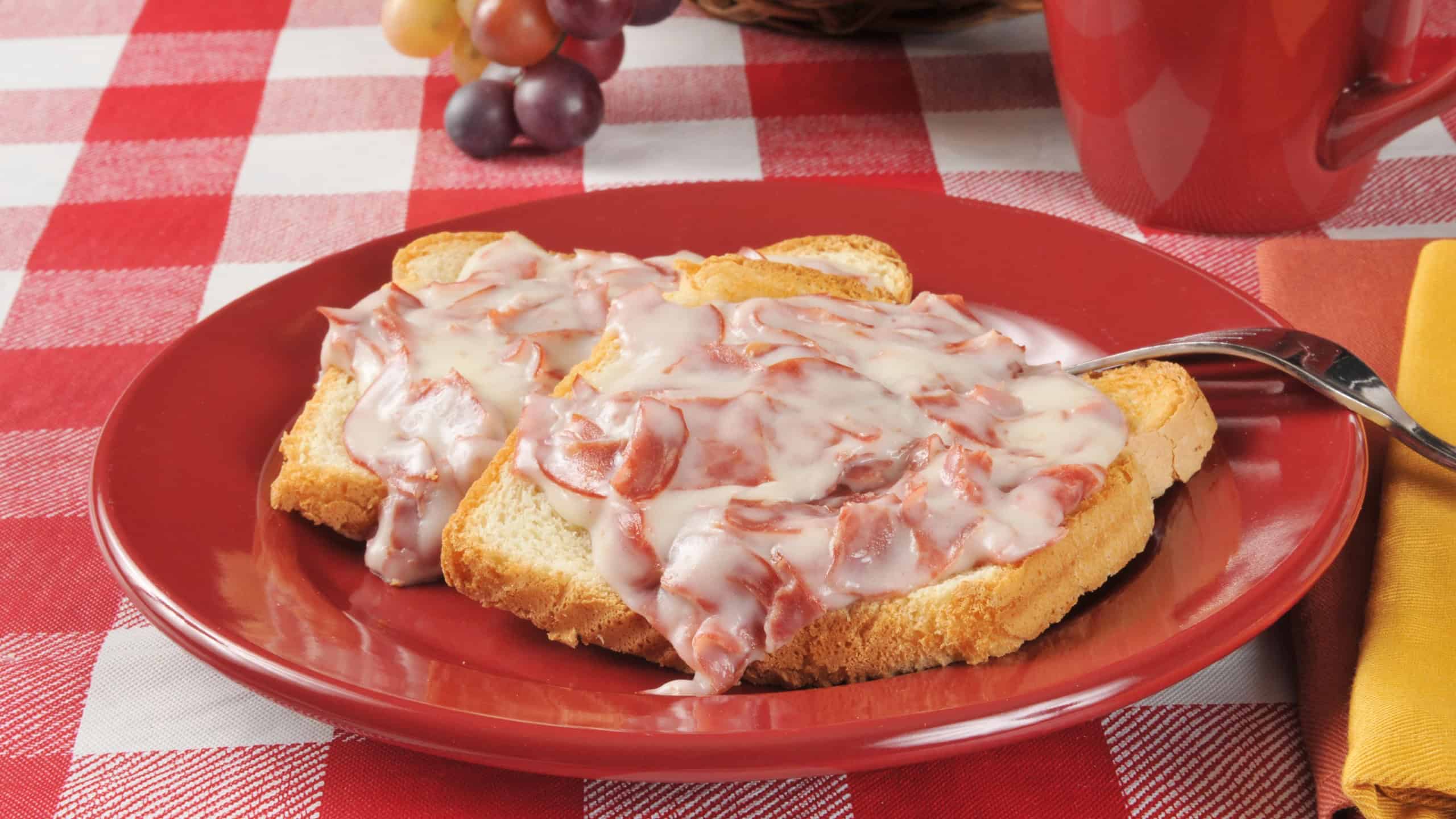 A plate of creamed chipped beef on toast with a drink