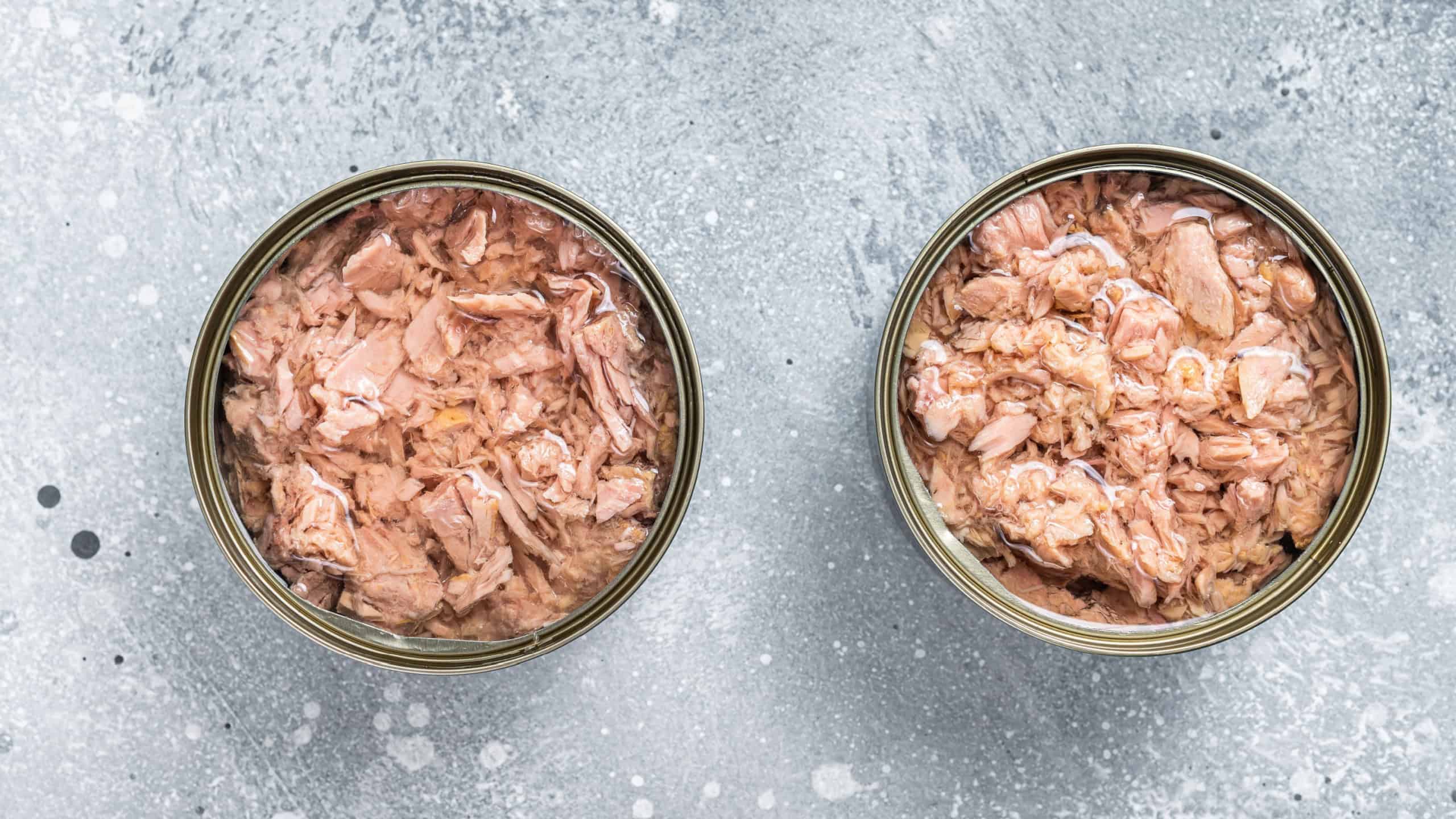 Open tin can with canned tuna fish. Gray background. top view