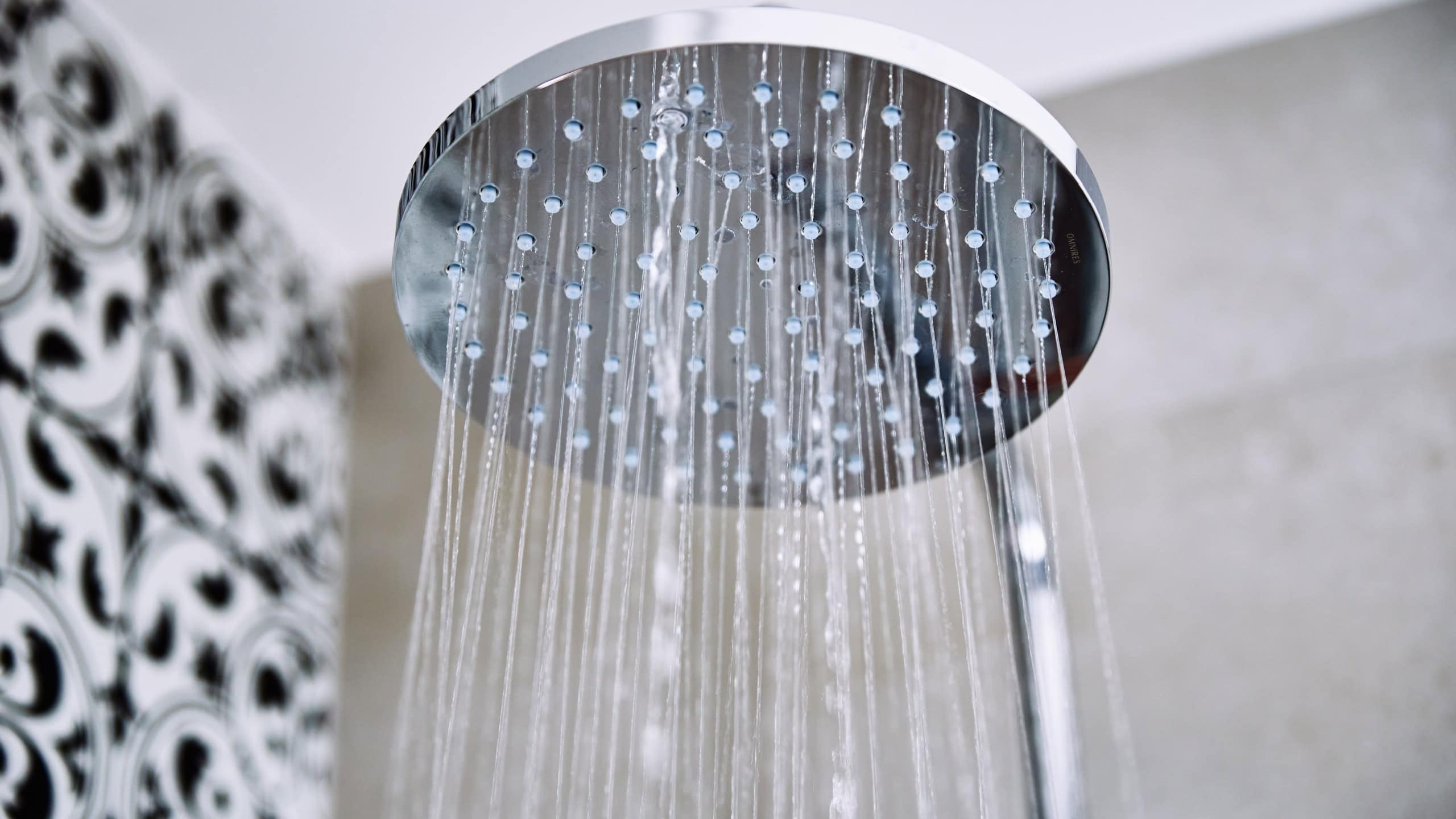 Modern shower with falling water drops in bathroom, closeup