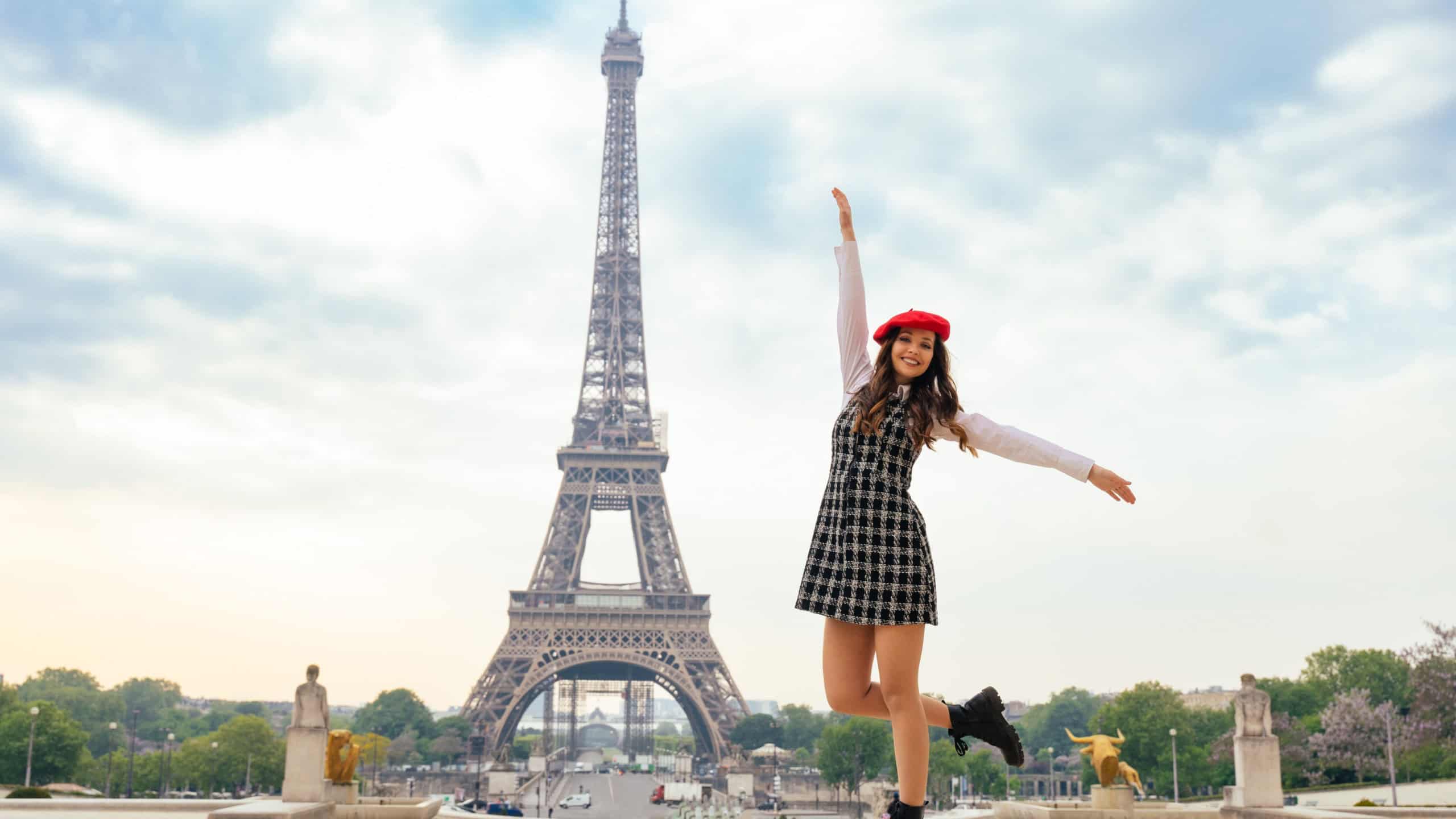 Beautiful young woman visiting paris and the eiffel tower. Parisian girl with red hat and fashionable clothes having fun in the city center and landmarks area