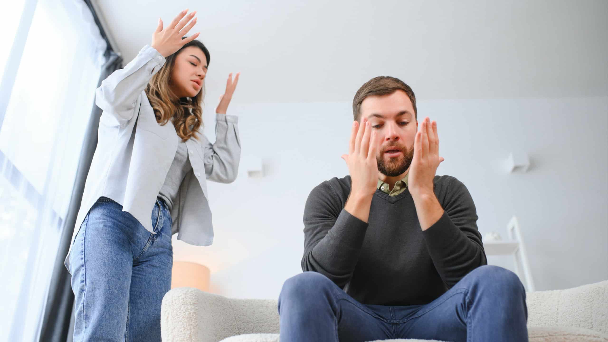Family quarrel, man and woman sitting on sofa at home. angry woman yells at her husband.