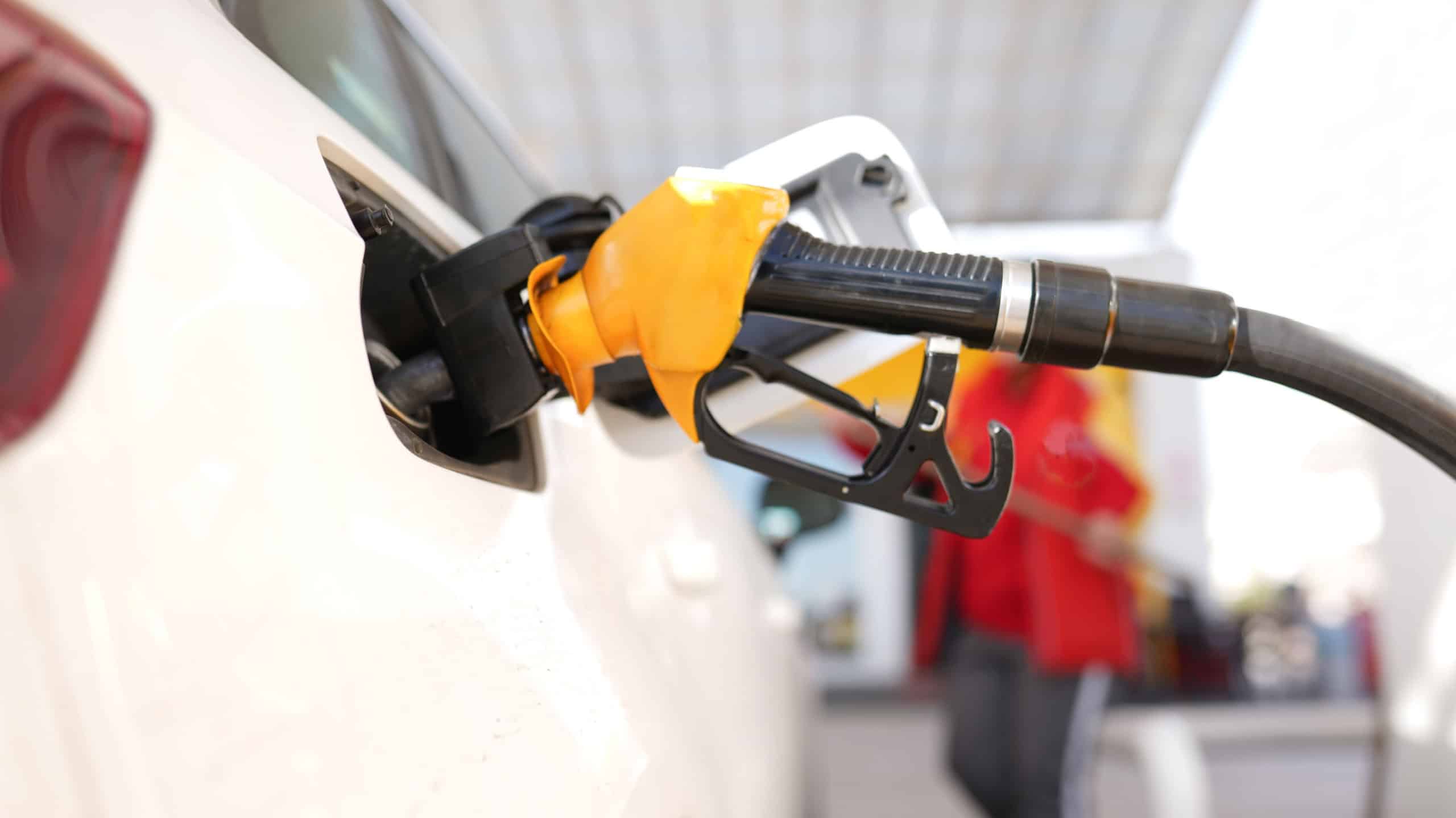 A car is being filled with gas at a gas station. The gas pump is black and silver