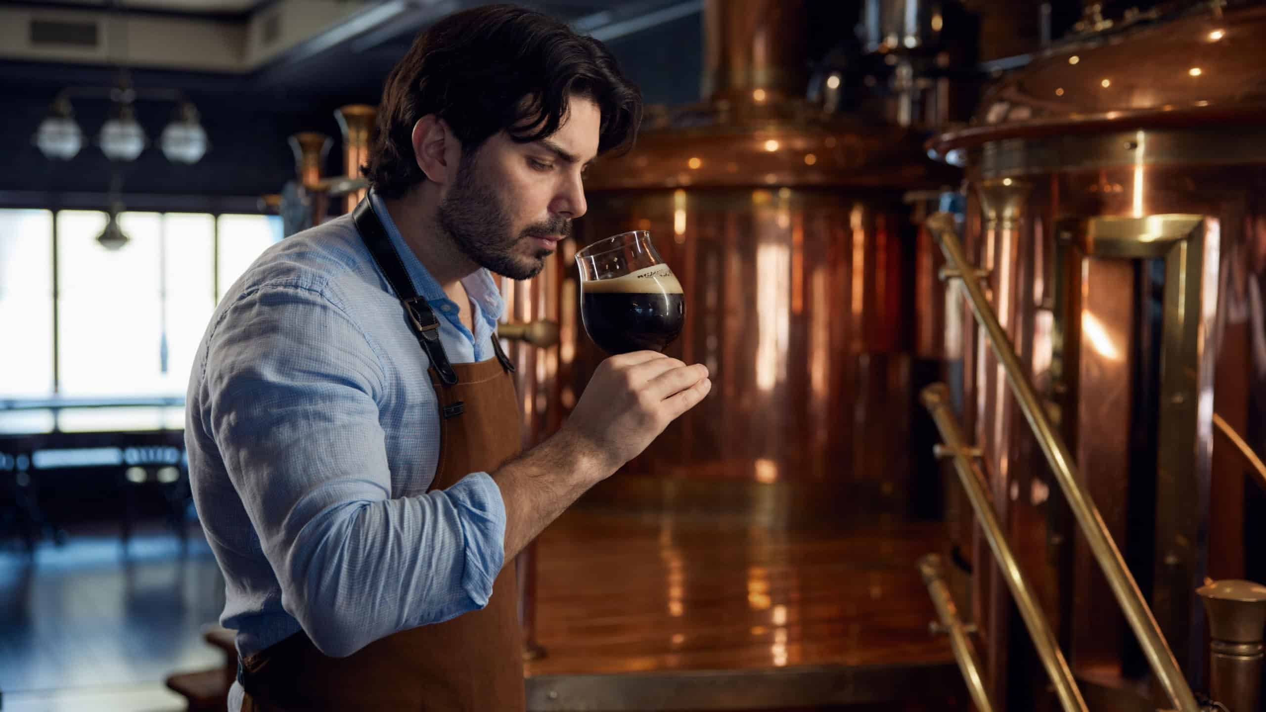 A man is taking in the aroma of a glass of beer in a brewery
