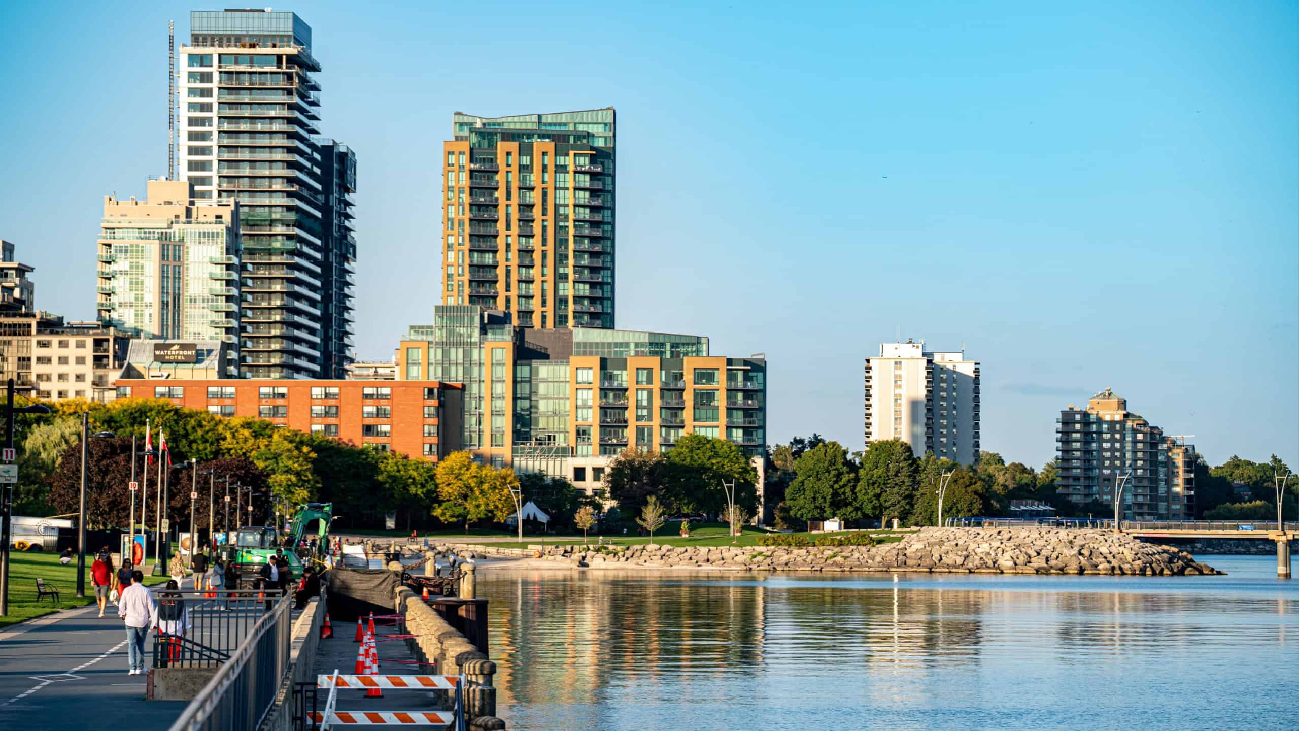 View of Burlington waterfront with modern buildings and people walking along the pier. Burlington, Canada - September 26, 2025.
