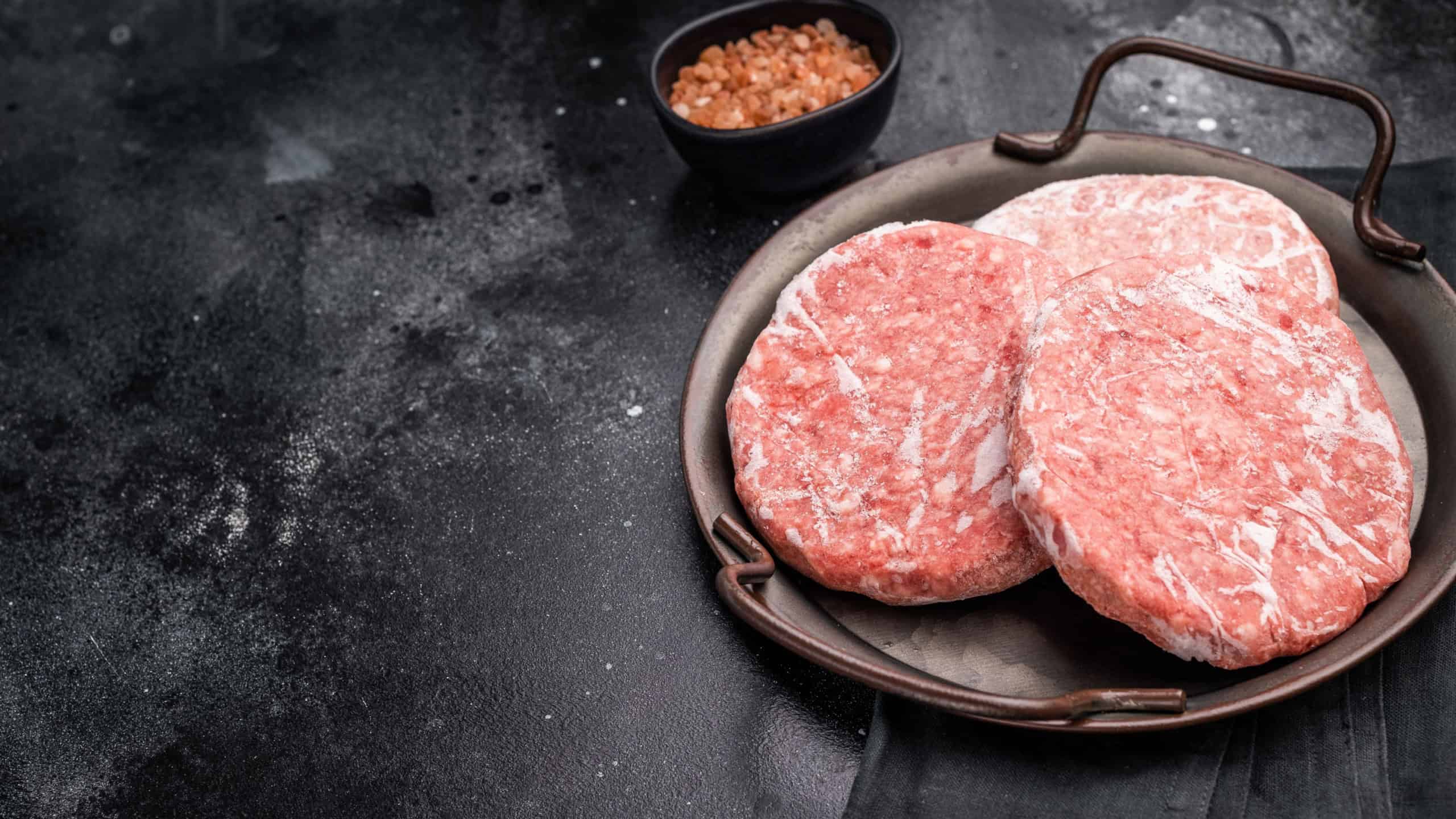 Frozen Meat cutlet, mincemeat of pork and beef for burgers. black background. top view.