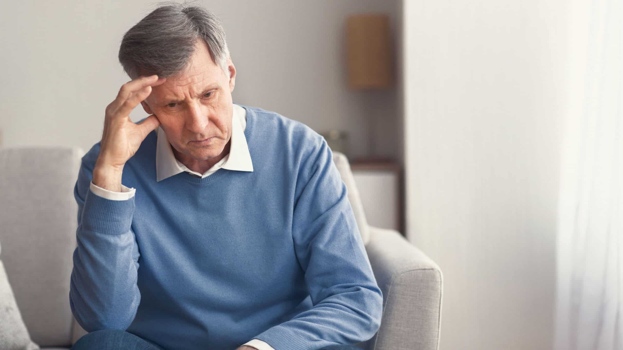 Unhappy Senior Man Thinking About Retirement Sitting On Sofa