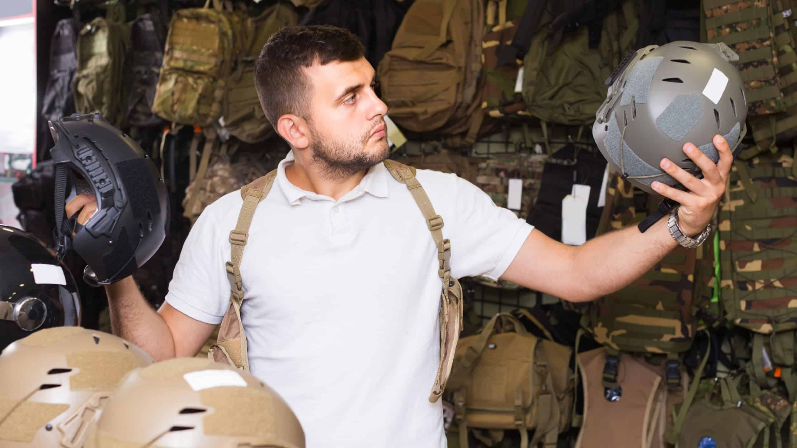 Young positive european guys choosing helmet in military shop