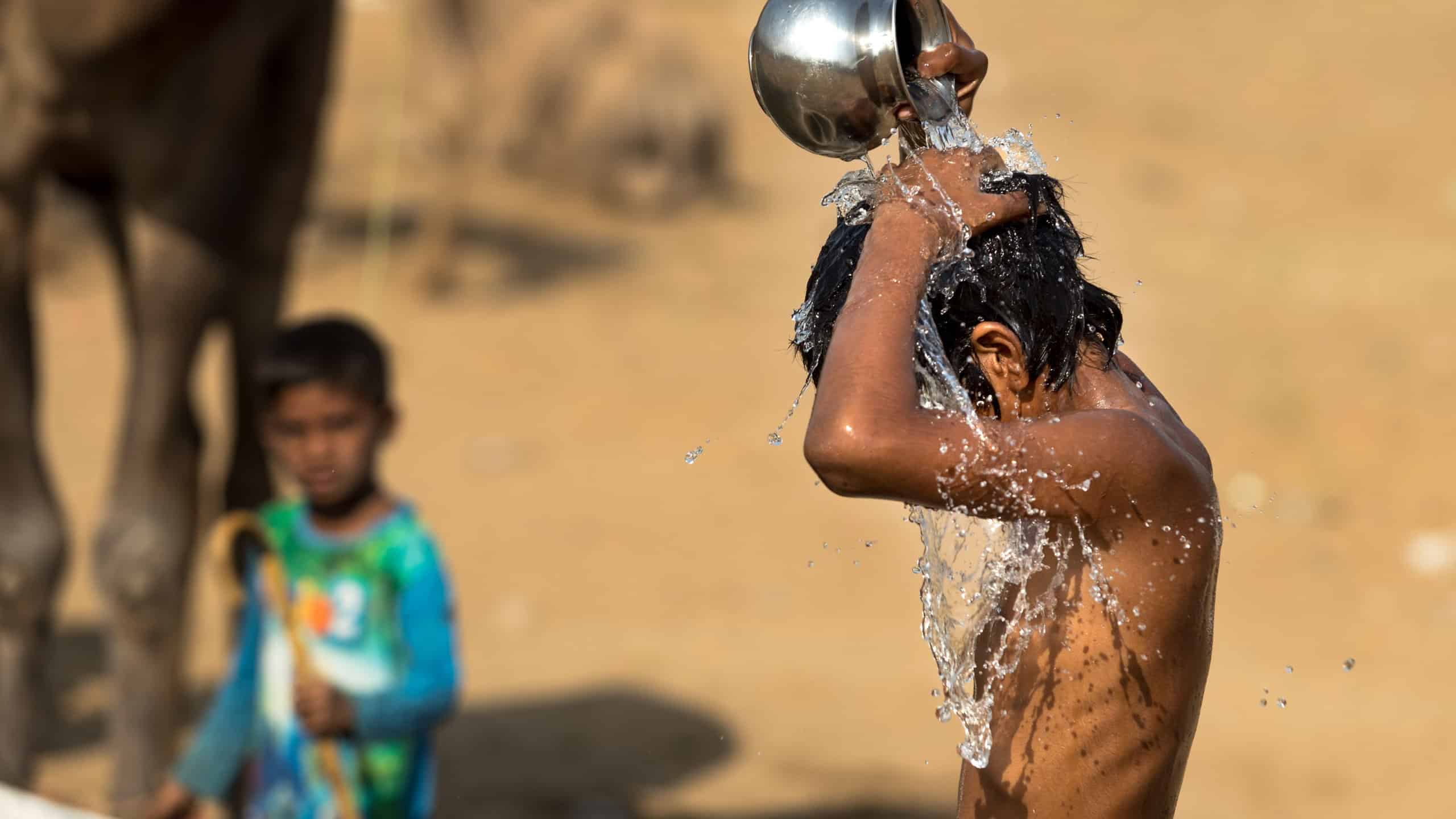 Bath in the desert.A child taking bath in watering trough or puddle in the desert, India. Water concept