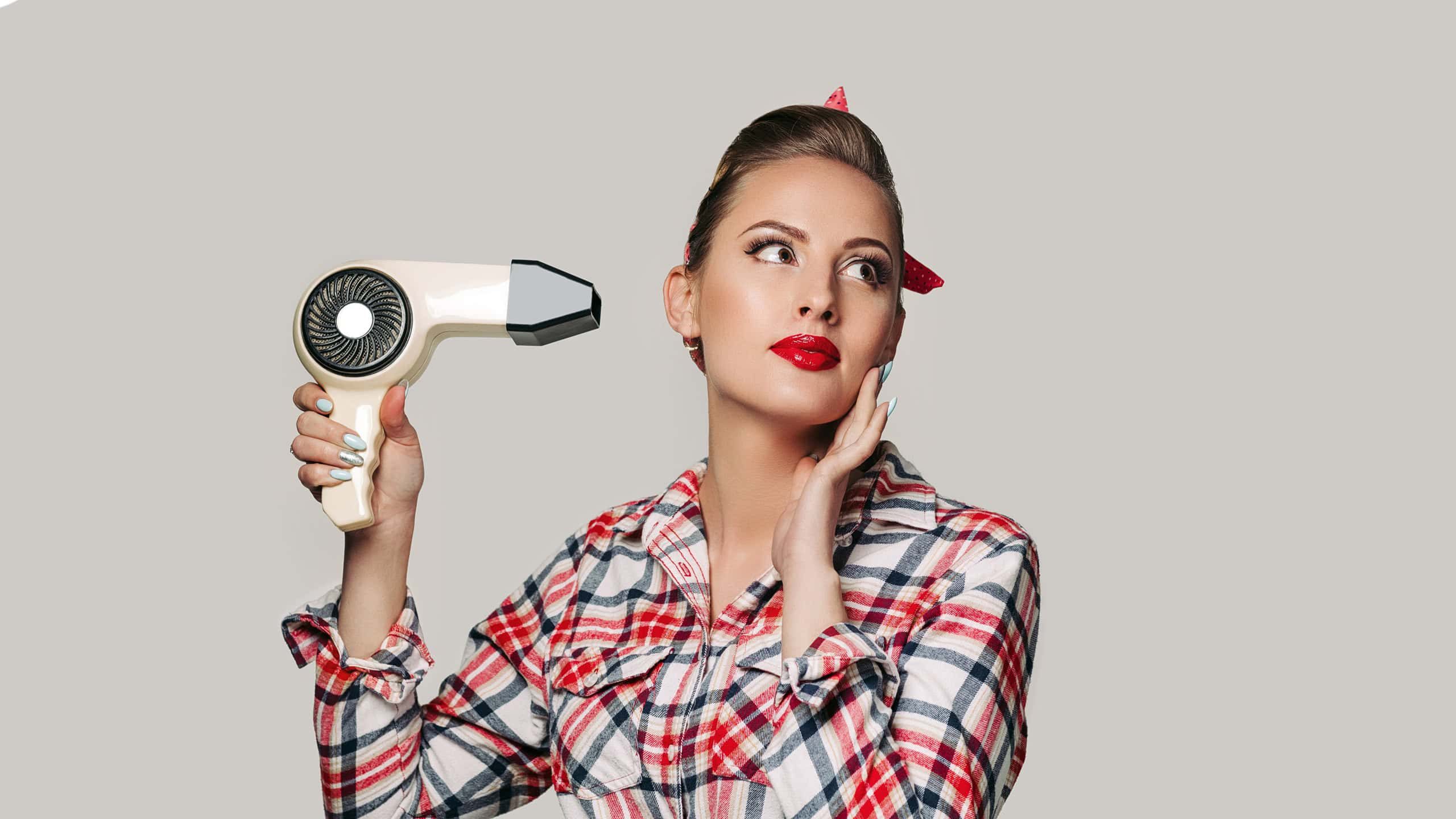 Happy young brunette woman with hair dryer. pin-up retro style