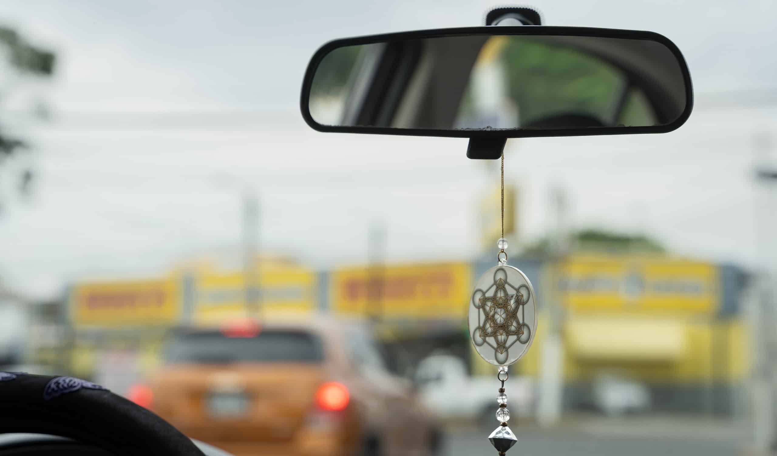 Geometric hexagon and circles pendant hanging on car inside mirror. Bad vibes protection symbol, superstition concepts