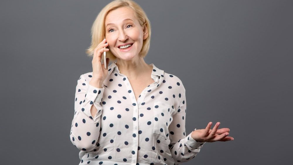 Phone conversation. Positive aged woman smiling while talking on the phone