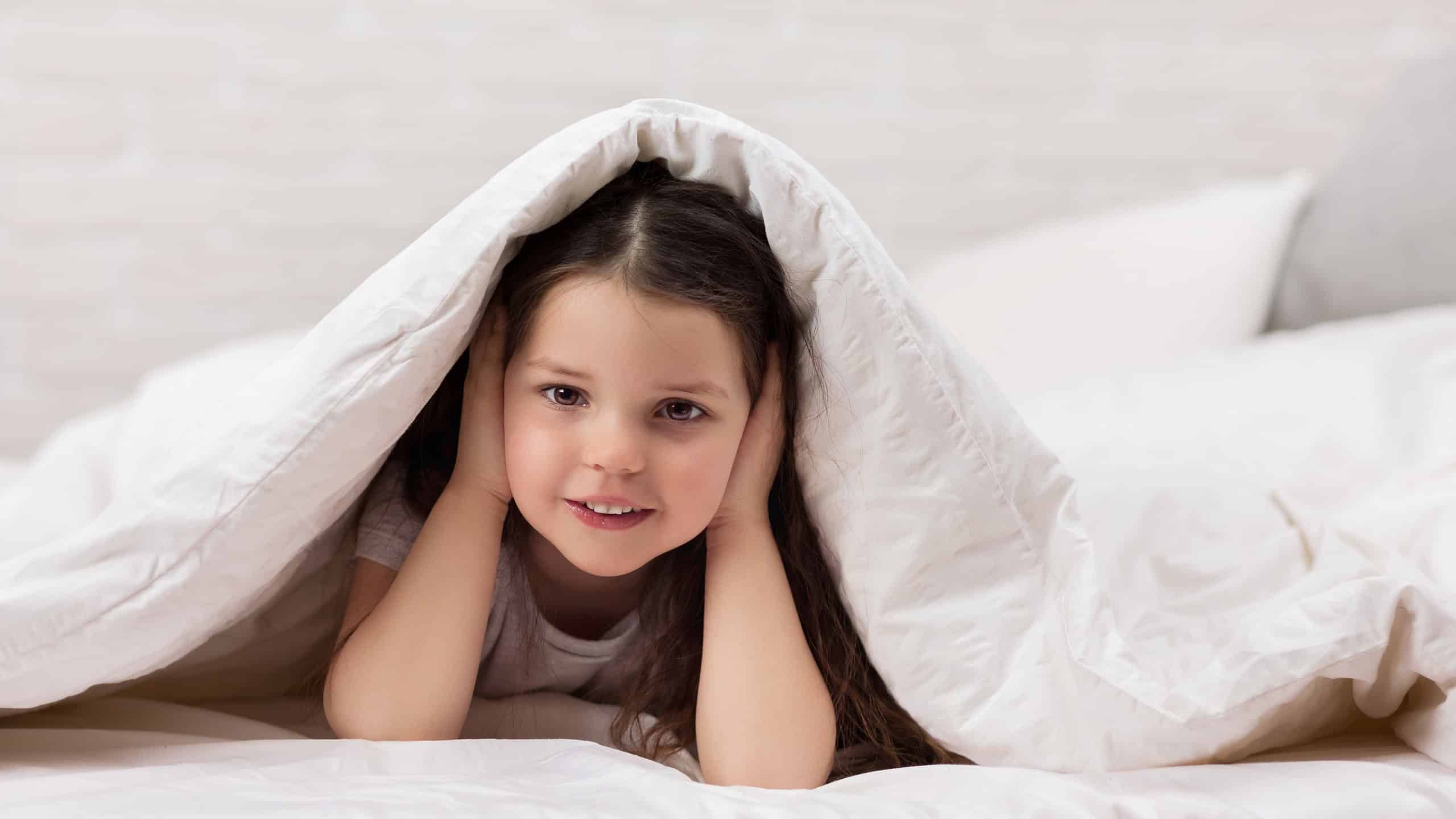 happy morning baby in bed. child dabbles in bed. child covers his ears