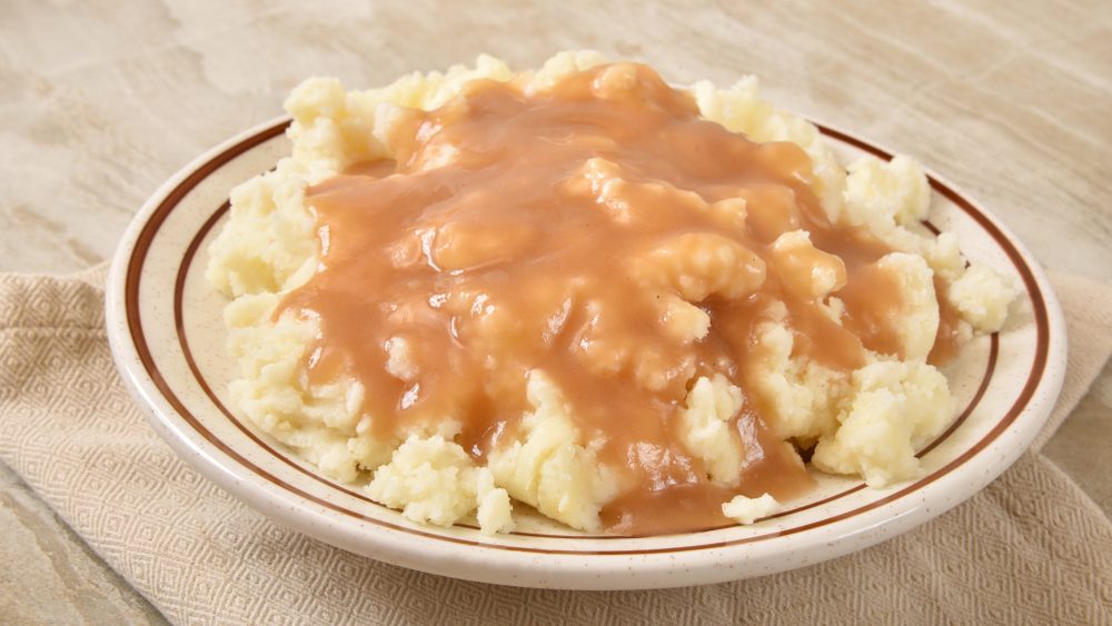 A serving bowl of mashed potatoes and turkey gravy
