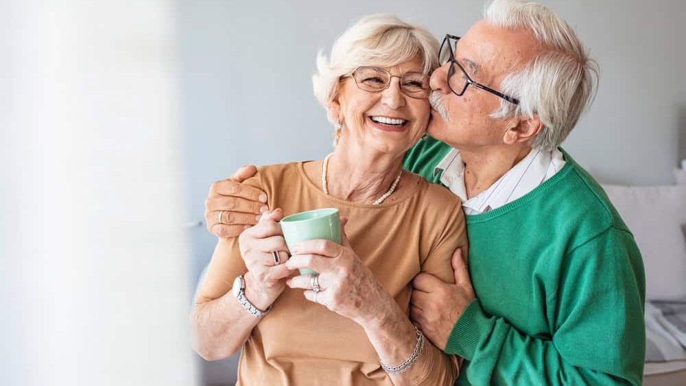 Portrait of smiling senior couple. Cropped portrait of a senior man affectionately embracing his wife at home. Senior man and woman standing in new house looking at camera