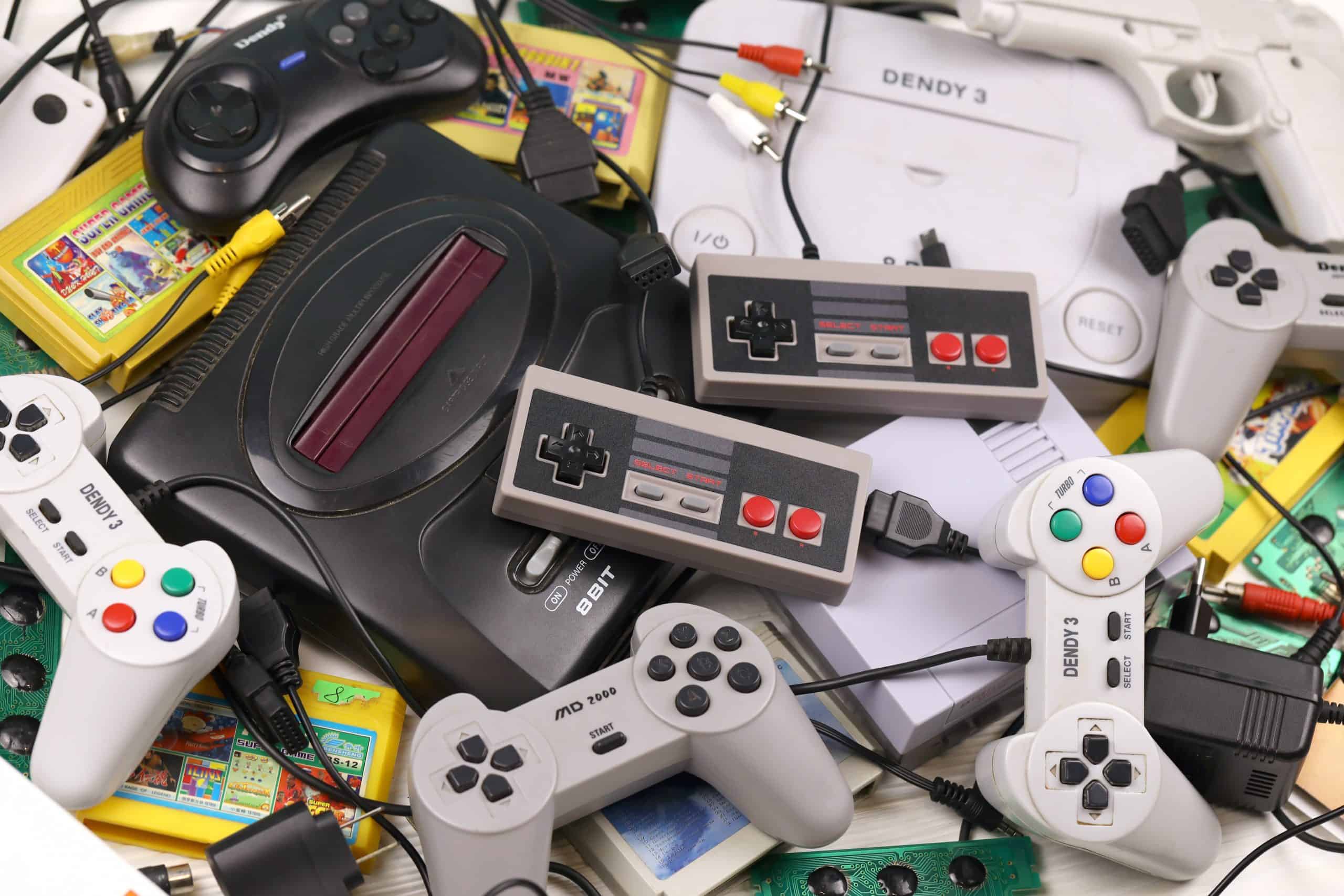 KHARKOV, UKRAINE - DECEMBER 27, 2020: Pile of old 8-bit video game consoles and many gaming accessories like a joysticks and cartridges. Old school retro gaming