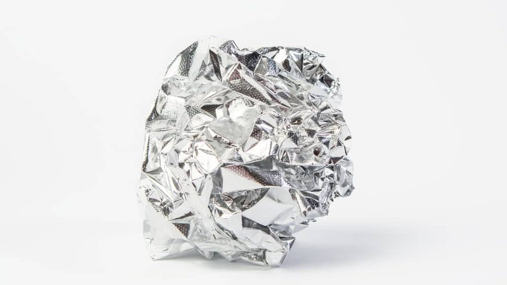 Crumpled piece of gray foil on a white background, close up