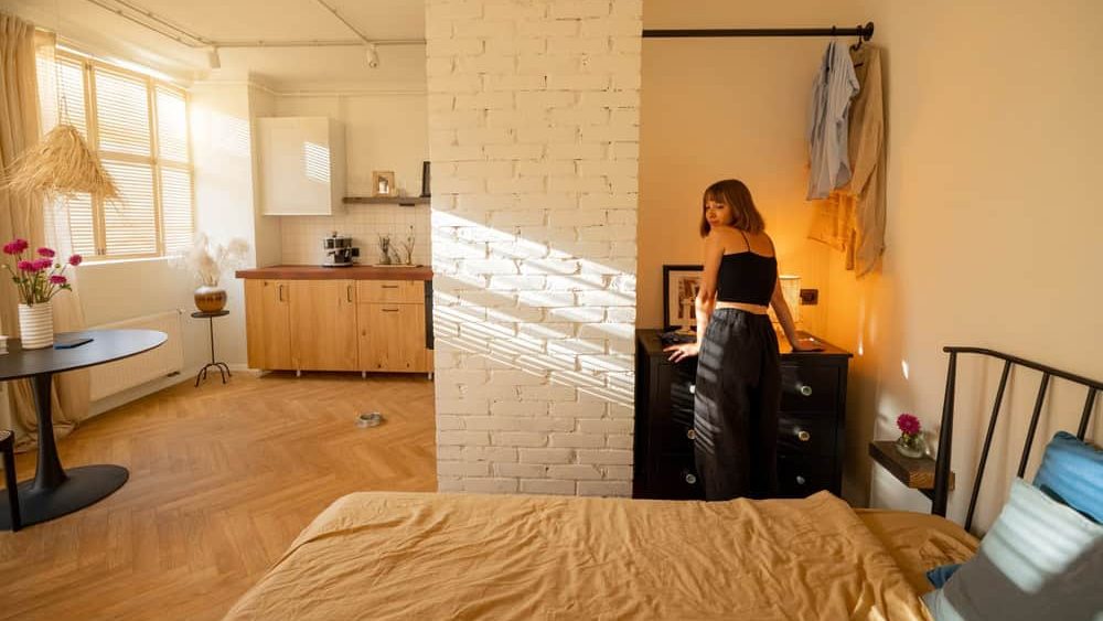 Woman is getting dressed in wardrobe of her tiny and stylish studio apartment. Interior design and domestic lifestyle conept
