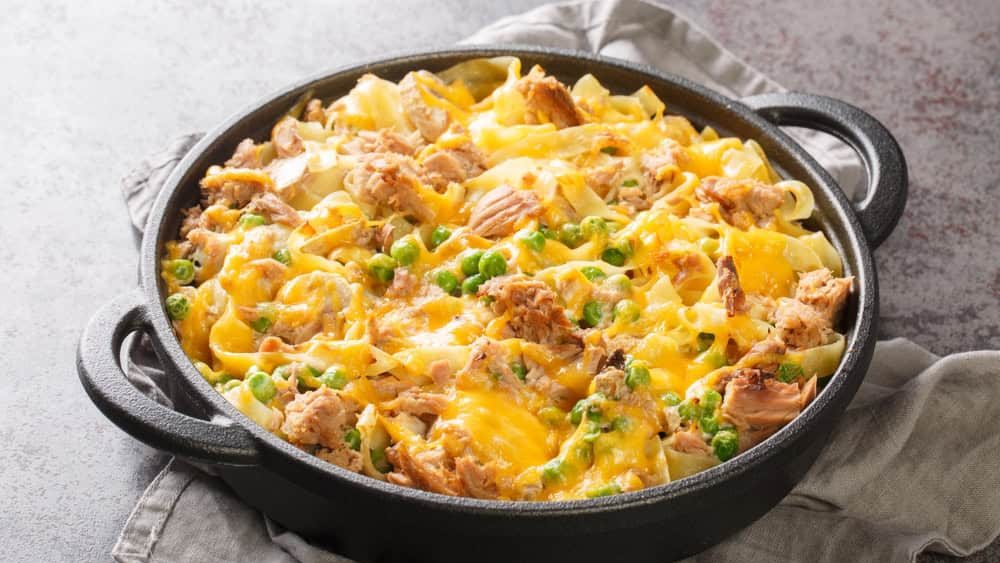 Homemade Cheesy Tuna Casserole with Peas and Egg Noodles closeup on the pan on the table. Horizontal