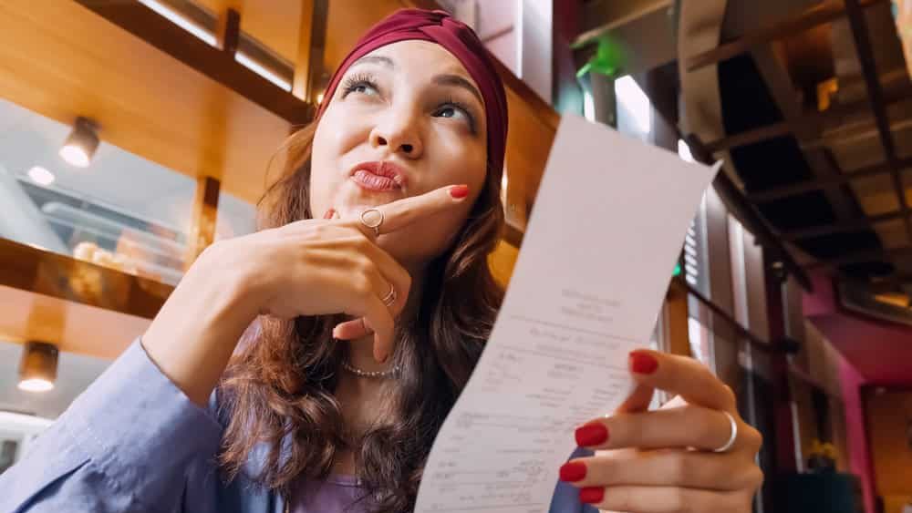 The girl's face was etched with a mix of confusion as she scrutinized the bill in front of her in restaurant. Something didn't add up, and she wasn't sure whether it was a mistake or a hidden charge.