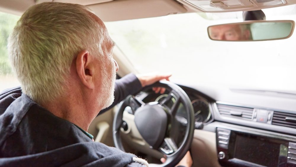 Retired elderly man traveling while driving car during road trip at vacation