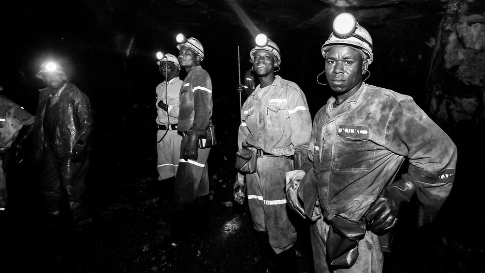 JOHANNESBURG, ZA - Sep 06, 2022: A group of people with mining equipment at the underground platinum mine in Johannesburg, South Africa, grayscale