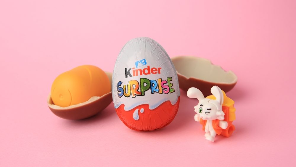 Slynchev Bryag, Bulgaria - May 25, 2023: Kinder Surprise Eggs, plastic capsule and toy bunny on pink background