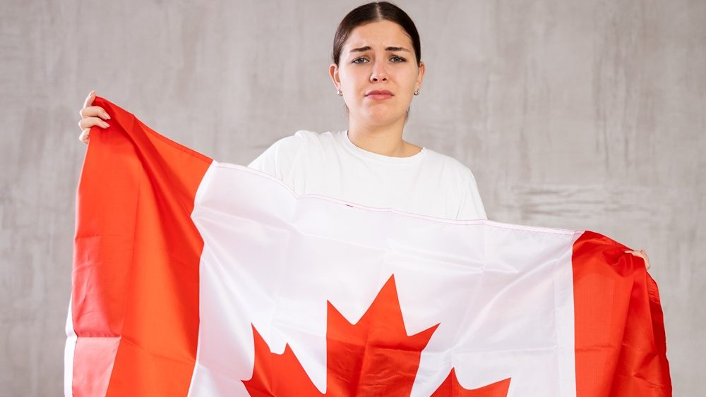 Young sad woman holding national flag of Canada in her hands